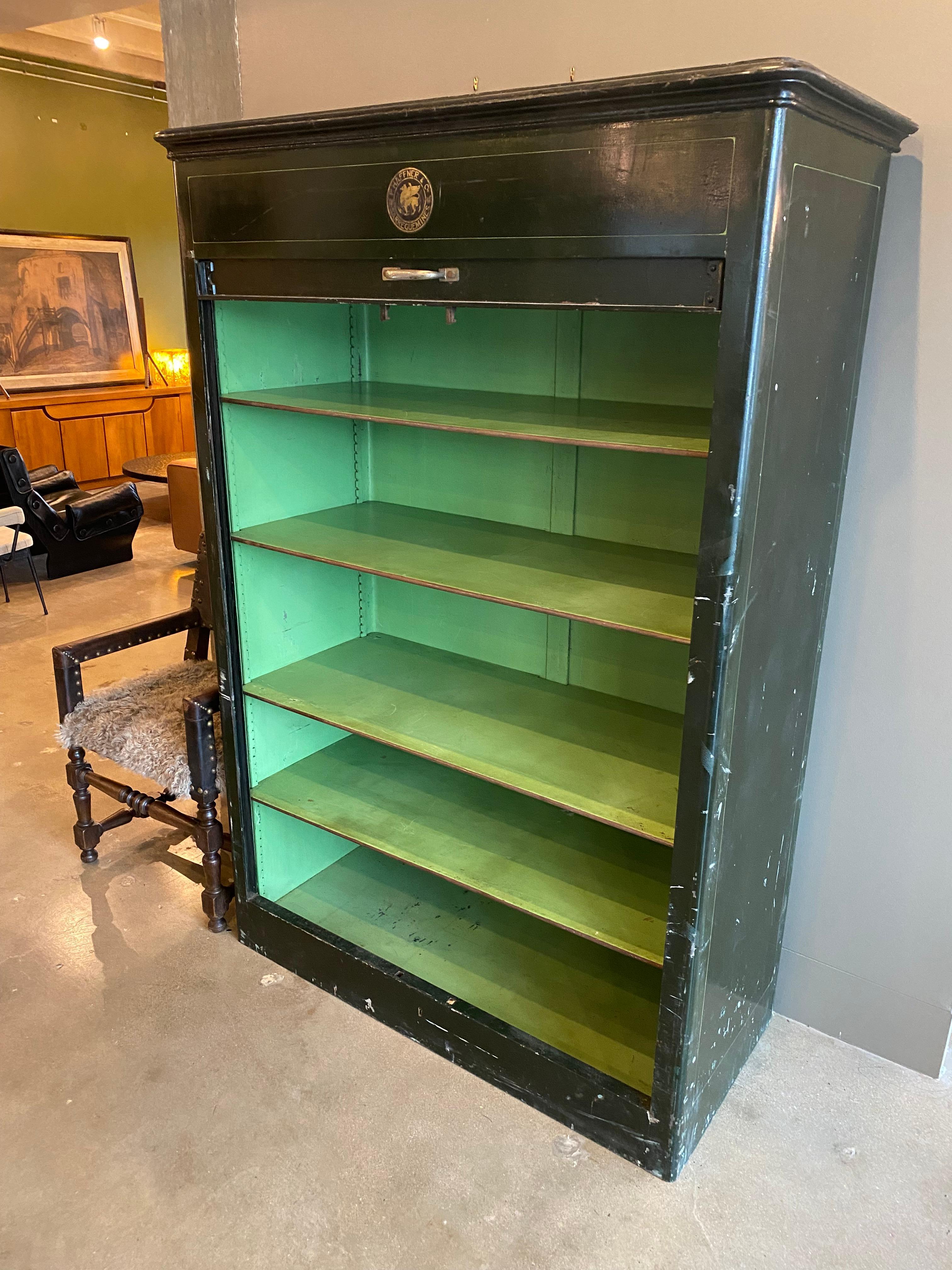 French industrial cabinet by hard-to-find maker, P. Haffner of Sarreguemines. Oversized steel structure in dark olive green with fine bright green interior and tambour door that rolls down from the top. Extraordinary color, brass hardware, label,