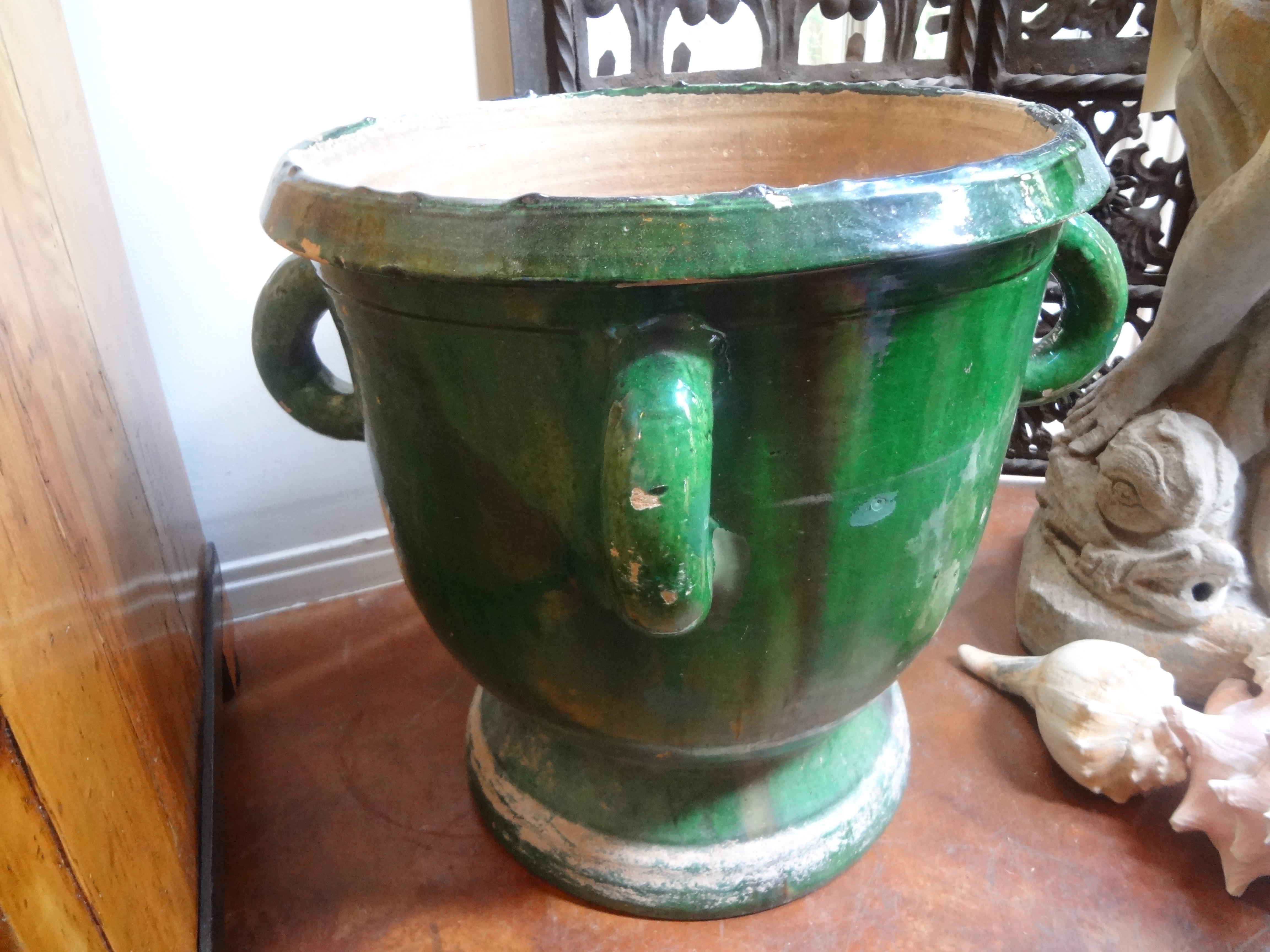 19th century green glazed planter or jardinière from Anduze, France with four handles and a footed base. This glazed earthenware planter from Provence has a beautiful green glaze that is worn in places but overall has a great patina. Dimensions