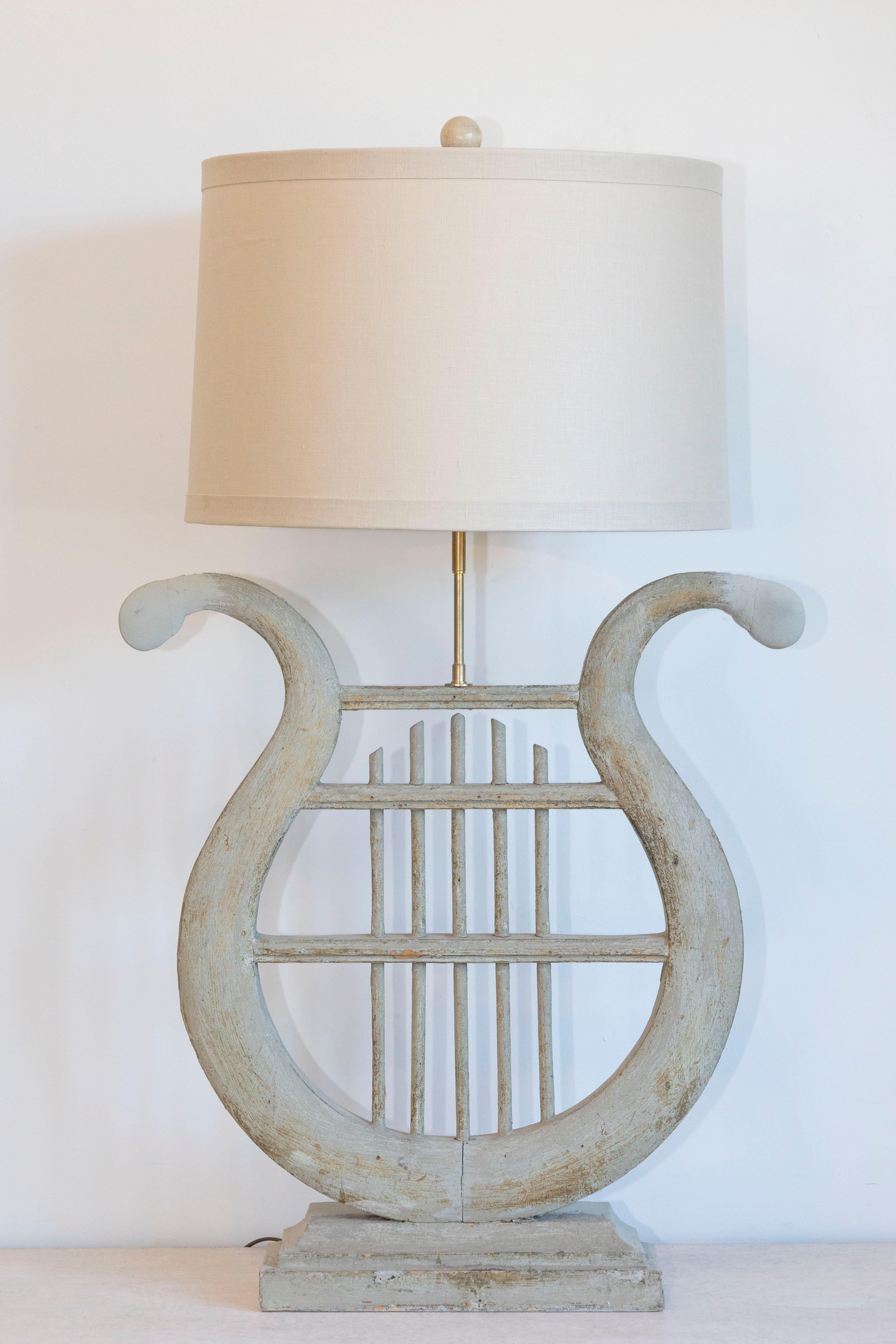 Cette exquise lampe française du XIXe siècle est un exemple frappant d'artisanat et de design intemporel, inspiré par la beauté classique d'une lyre. La base en bois sculpté est méticuleusement façonnée en forme de lyre, avec des bras gracieusement
