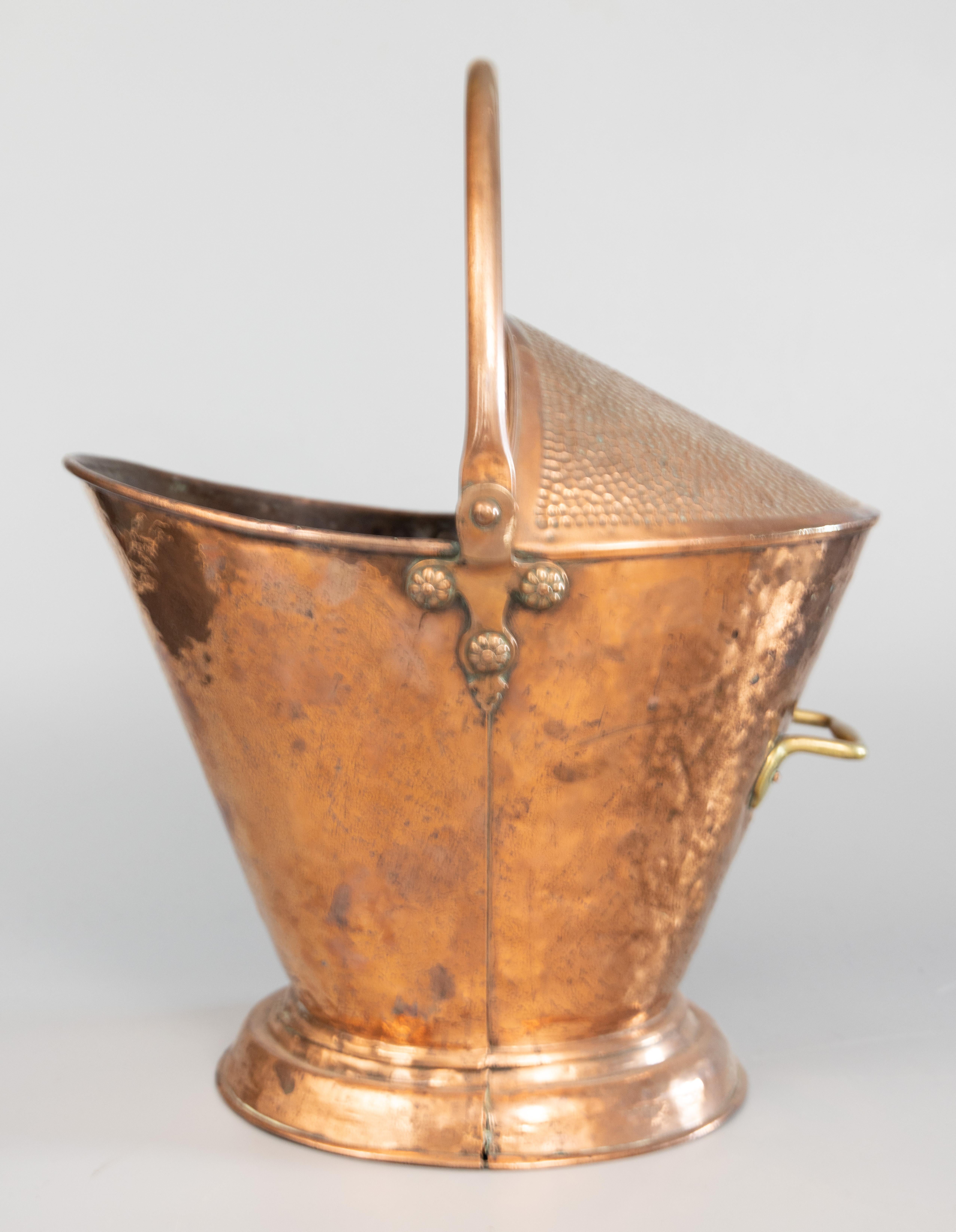 A superb 19th-century English hand hammered copper and brass helmet coal hod scuttle bucket / firewood holder / jardiniere. This fine hand crafted bucket is a nice large size, solid and well made, with a brass riveted swing handle and a lovely