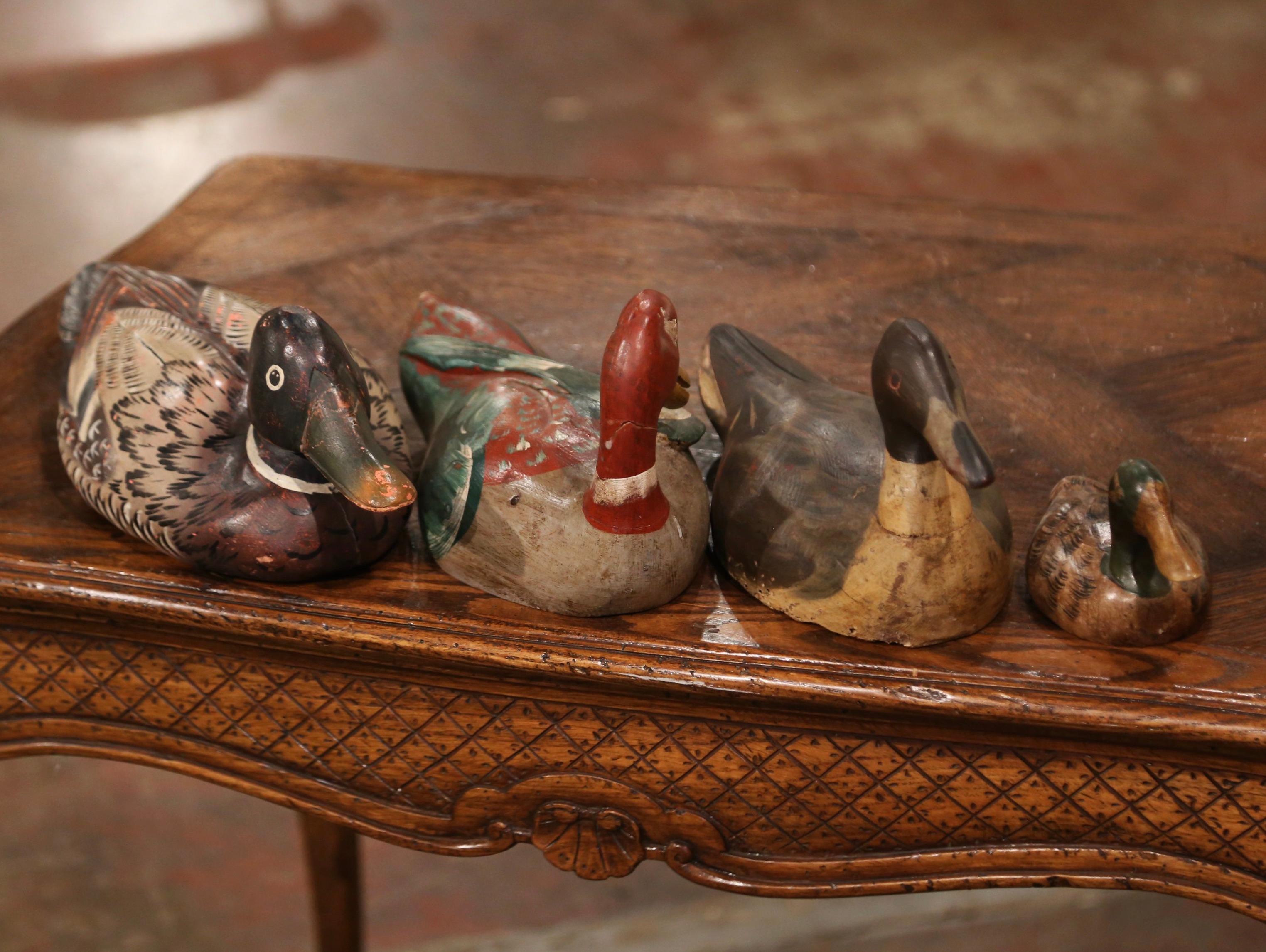 Decorate a man's office with this exquisite set of four antique wooden ducks. Crafted in France circa 1880, these duck decoys are of varied sizes and species, each colorful carved sculpture is nicely hand painted in the green, red, brown, beige and