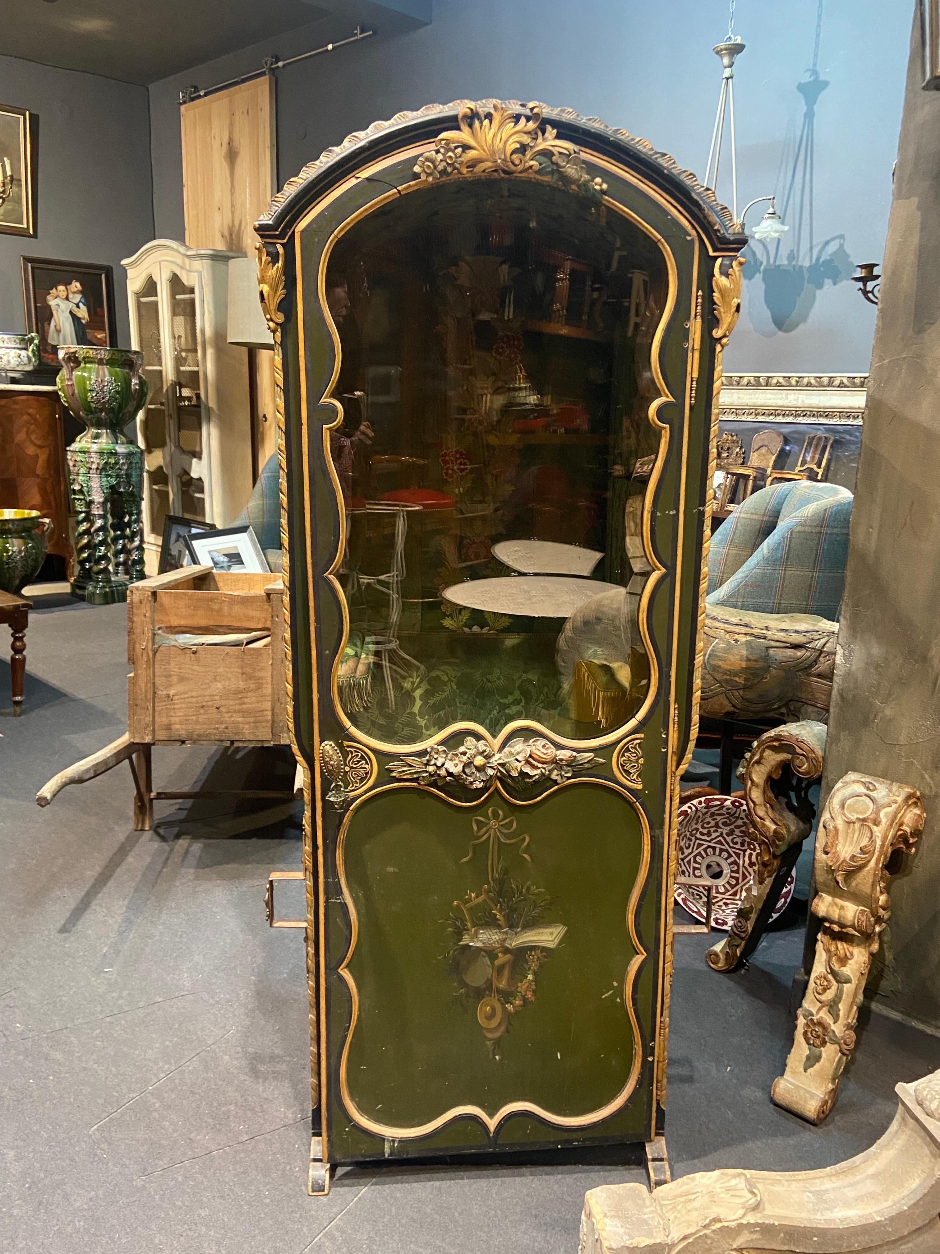 19th Century French sedan chair made of hand carved gilded wood hand painted with music trophy, wedding rings at the back and lots of flowers all around. It opens with a beveled original glass door. The interior lined with green silk brocade and