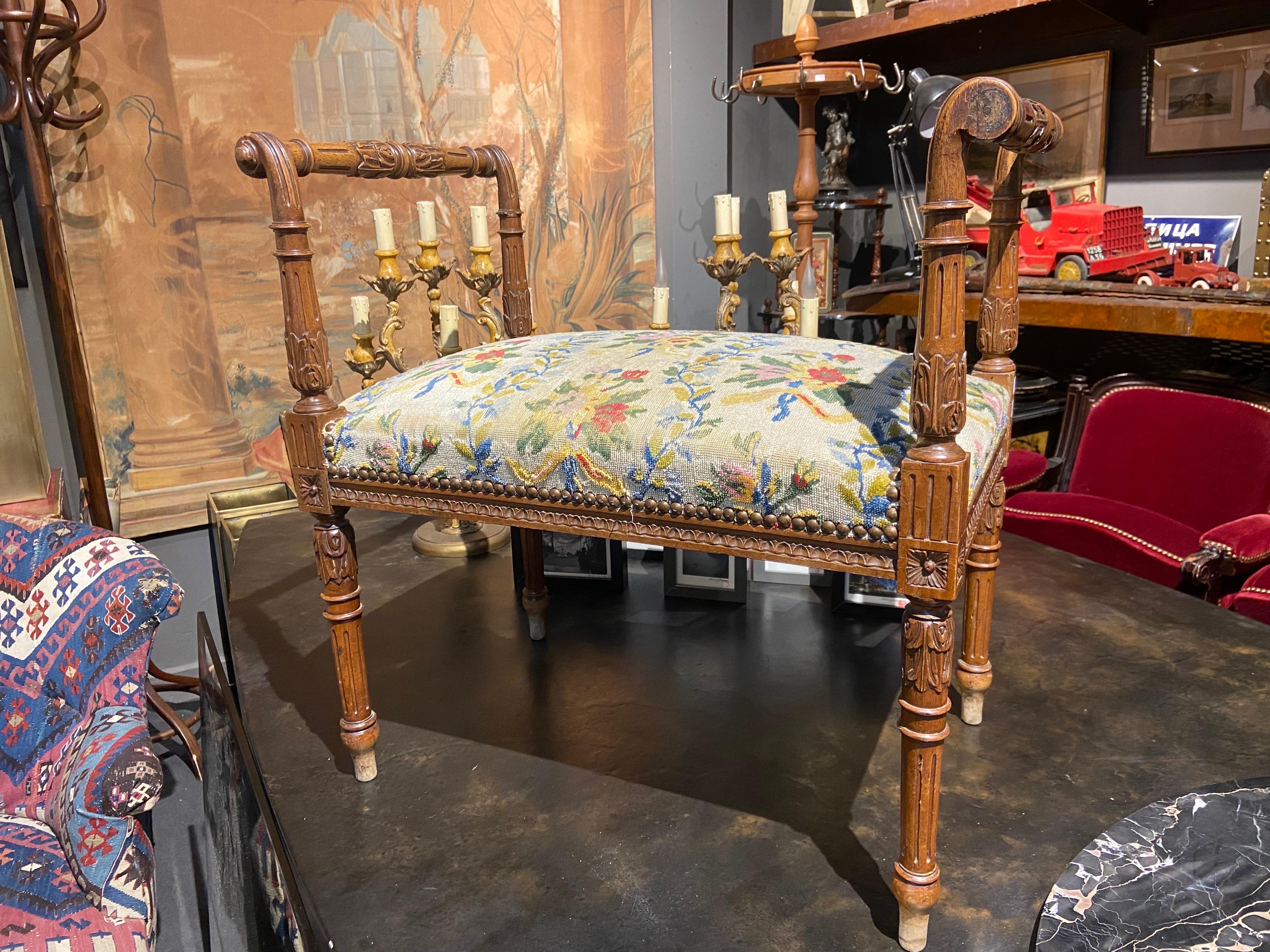 19th Century stool or piano bench, in molded, carved and stained beech, the baluster armrests decorated with acanthus leaves ending in scrolls, the belt decorated with a frieze of oves, the connecting dice decorated with daisies, resting on fluted
