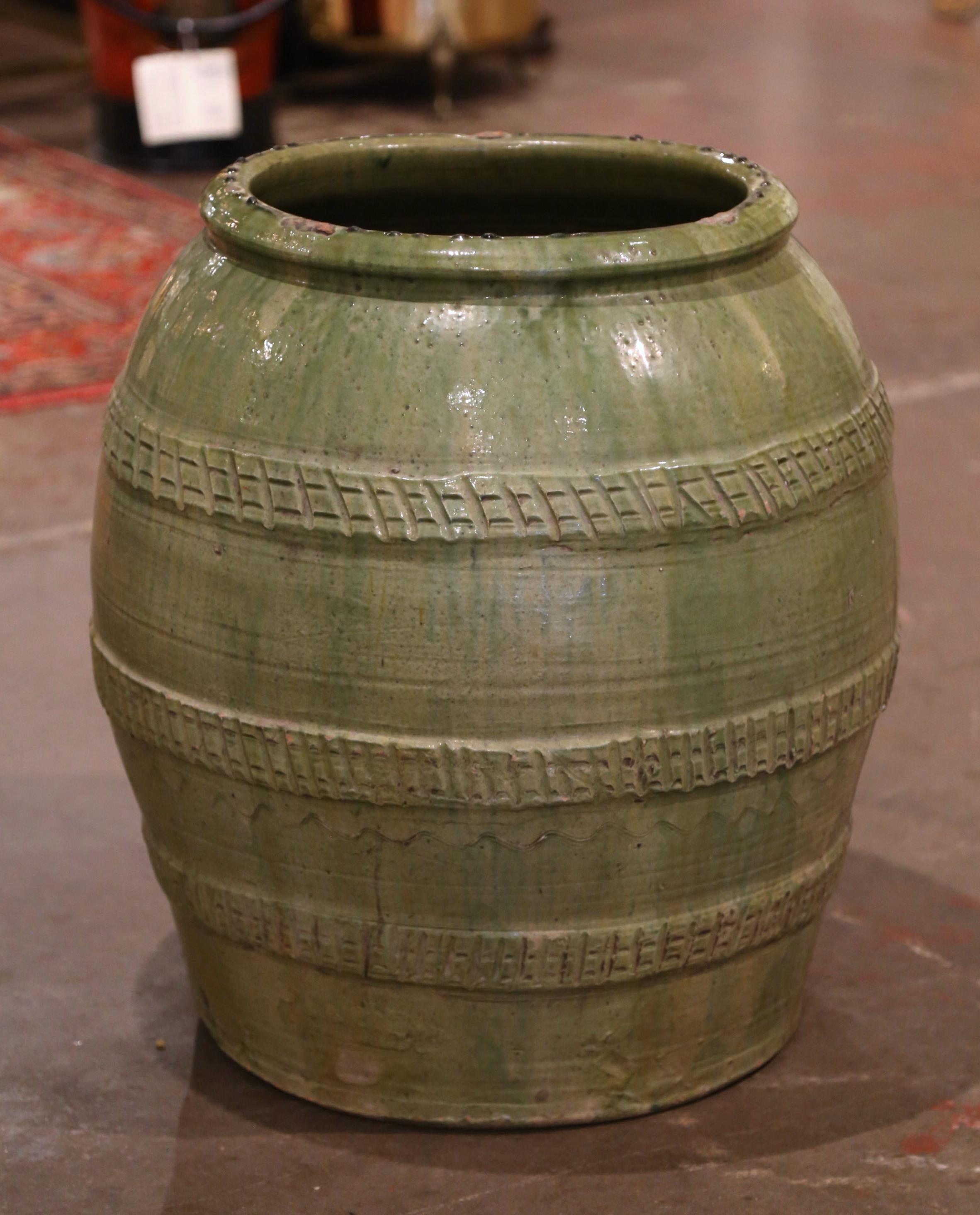 This large, antique earthenware jar was hand made in Southern France, circa 1870. Built of clay and finished with the traditional Provencal green glaze throughout, the terracotta pot is round in shape with a thick rim at the top, and decorated with