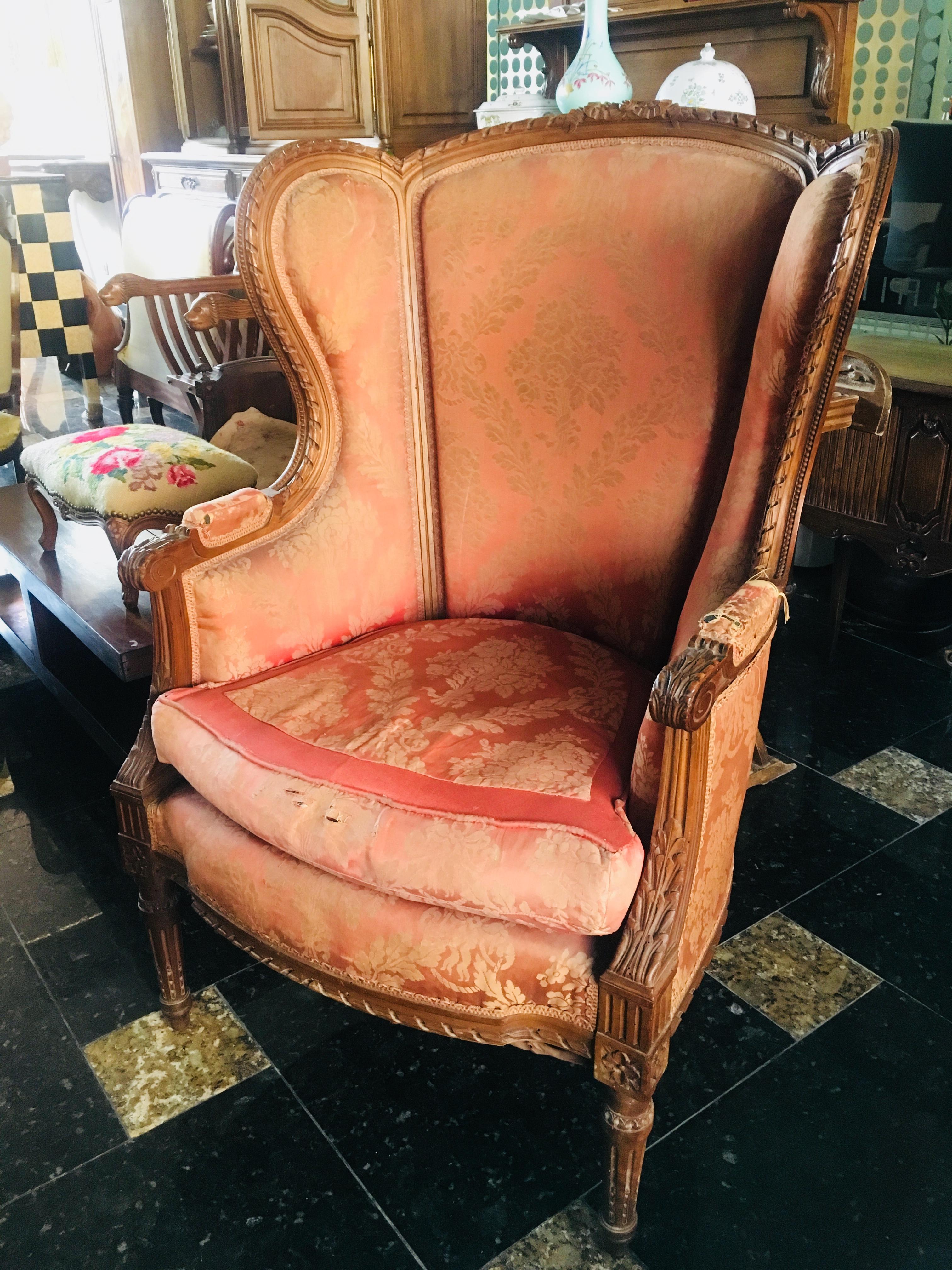 Antique French Louis XVI style Bergère à Oreilles, circa 1860, featuring wonderful hand-carved neoclassical details carved into the frame with upholstered back, arms, seat, and loose down cushion. Very comfortable seating. Chair is in very good