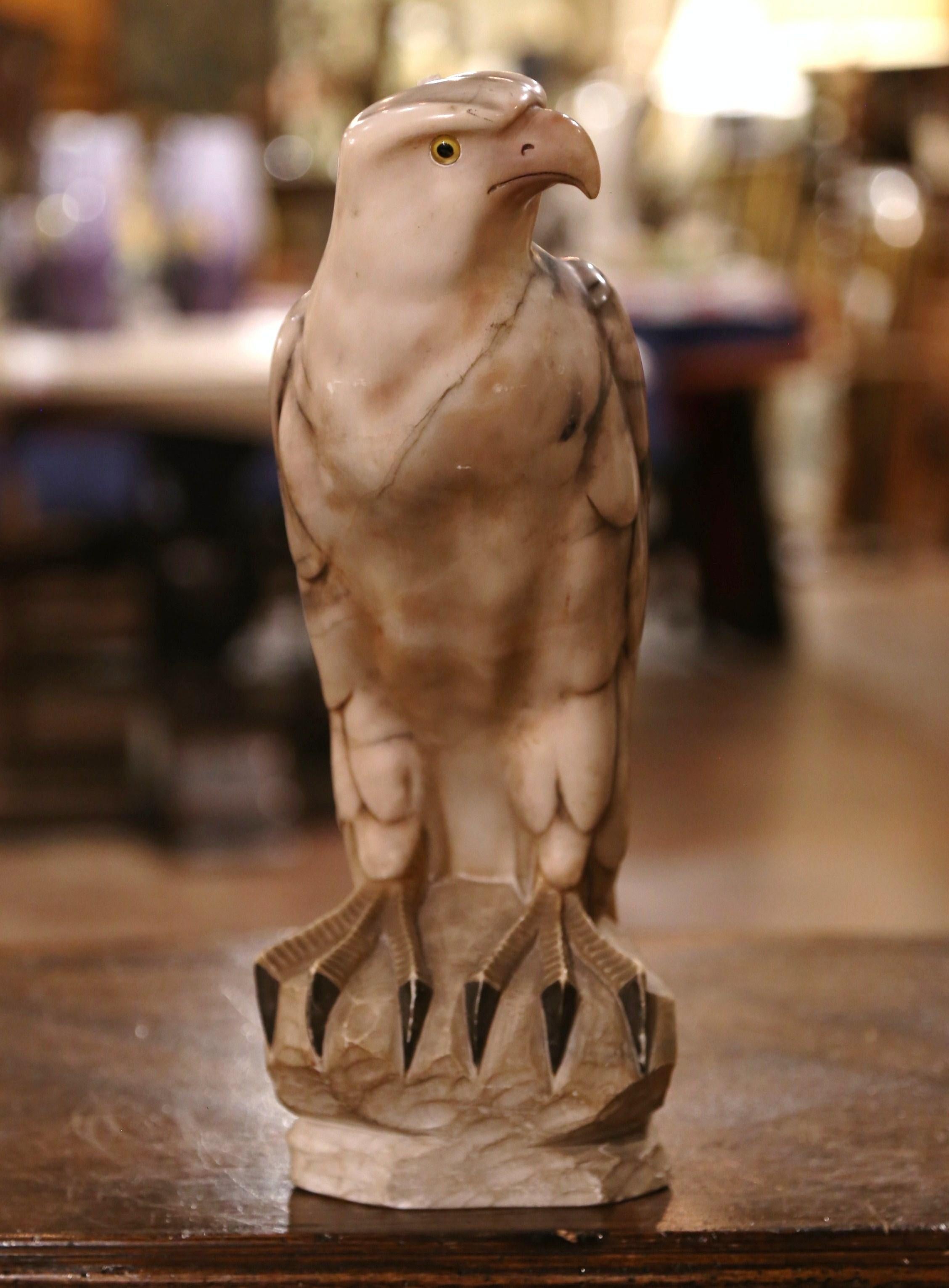 Decorate a shelf or a man's office desk with this stately antique marble eagle. Created in France circa 1870, and carved of variegated marble, the tall sculpture depicts a proud bird standing on a rectangular rock with his head turned. The avian
