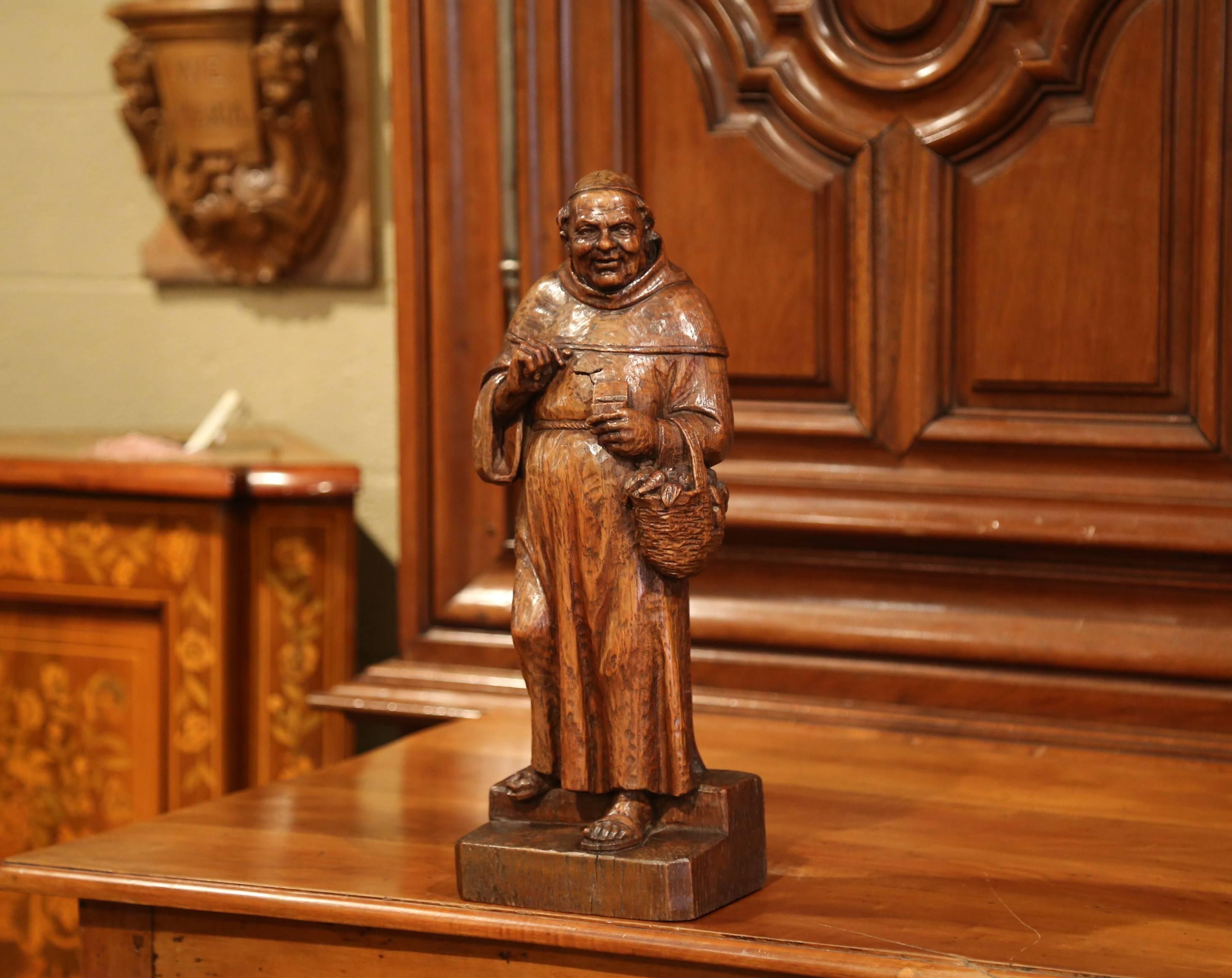 Decorate an office or a bar with this exquisite wooden carved statue. Crafted in Southern France circa 1850, the large fruitwood figurative sculpture features a monk in traditional cassock and sandals holding a vegetable basket and a box in his left