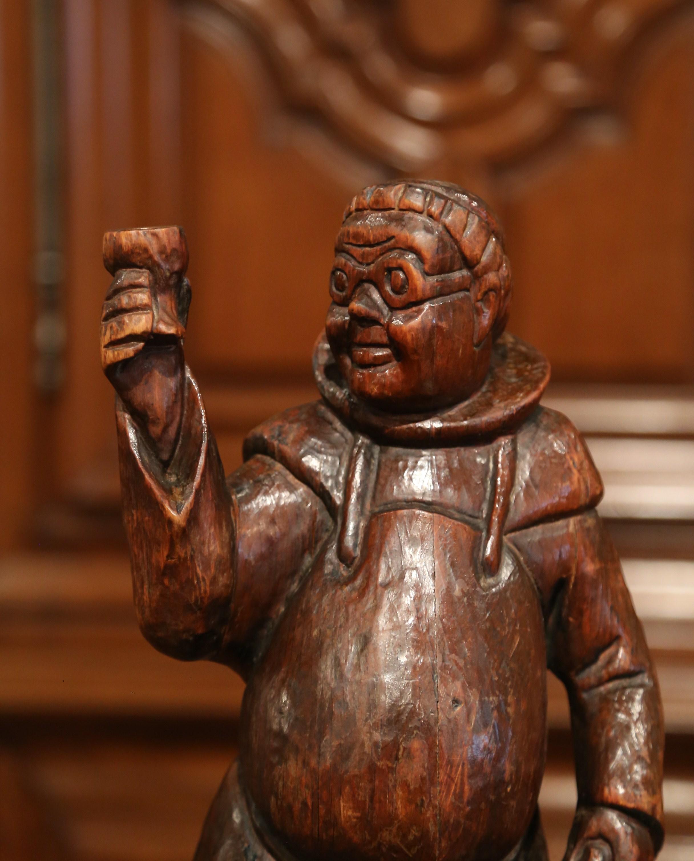 Decorate a bar counter or a wine cellar with this large wood figure. Crafted in Southern France, circa 1870, the carved figurative sculpture features a standing monk in traditional cassock and sandals holding a wine jug in his left hand while