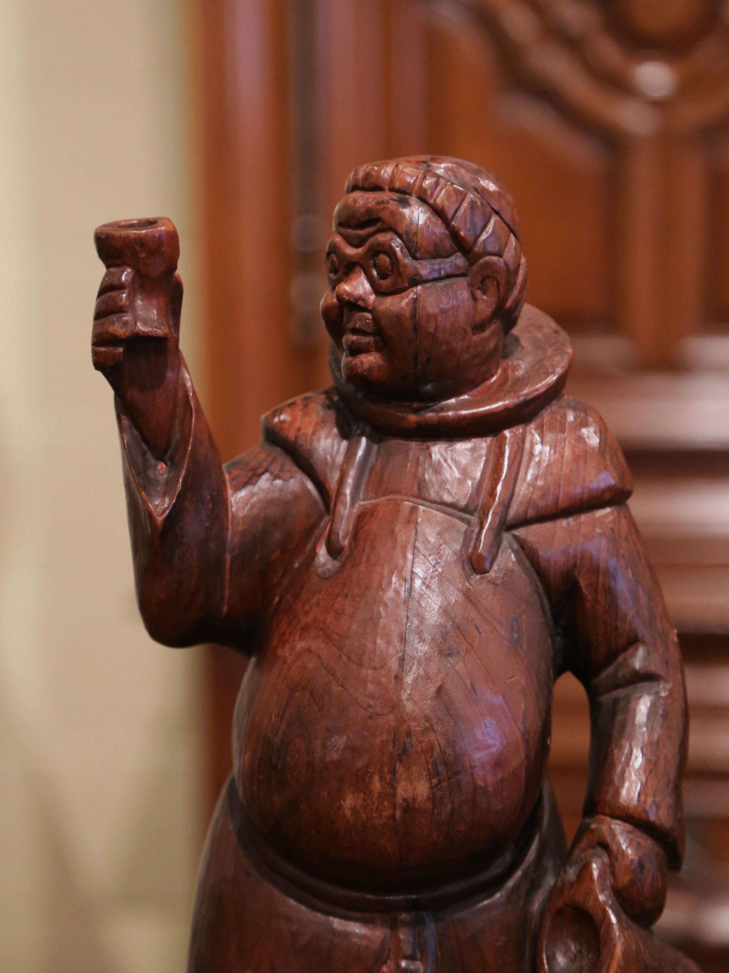 Decorate a bar counter or a wine cellar with this large wood figure. Crafted in Southern France, circa 1870, the carved figurative sculpture features a standing monk in traditional cassock and sandals holding a wine jug in his left hand while