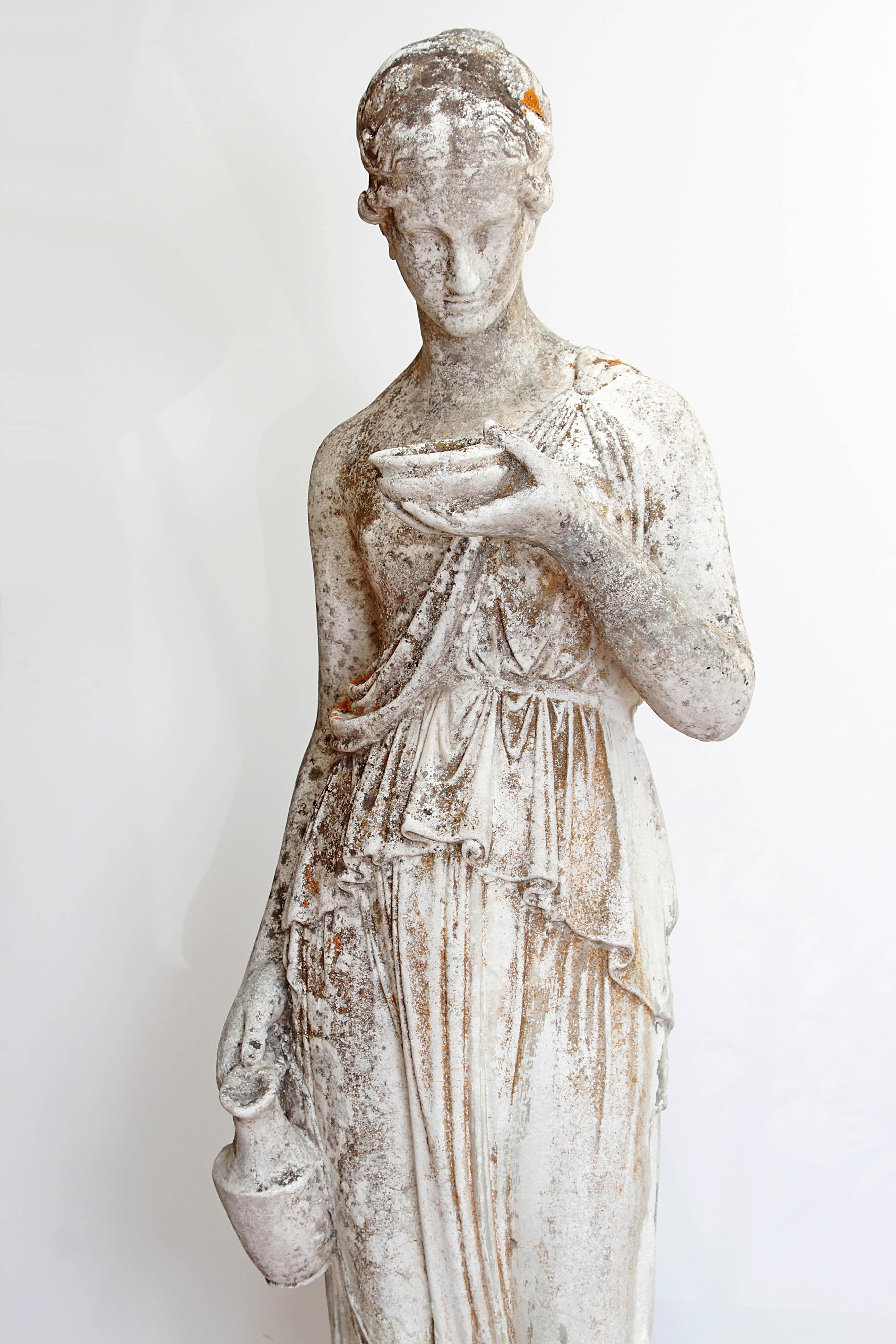 A 19th century French hand carved stone life-sized statue of a classical maiden holding a jug and a bowl.  Historically, the statue has been displayed in a garden and has significant but attractive weathered patina with past professional