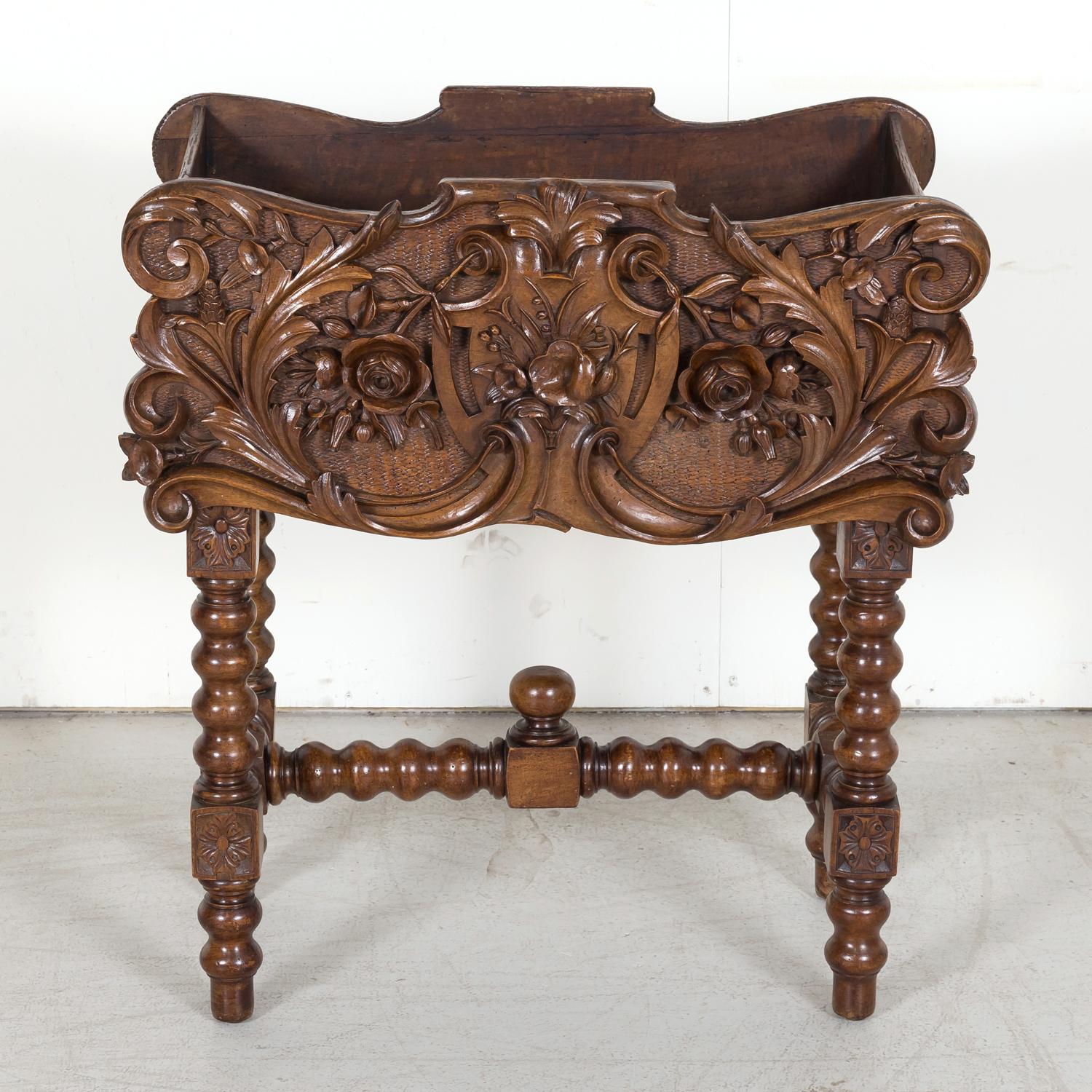 A 19th century Black Forest jardinière hand carved of solid walnut in the Alsace region of France, circa 1870s. The detailed, intricately carved wood planter features a realistic hand carved basket weave background with a center cartouche and floral