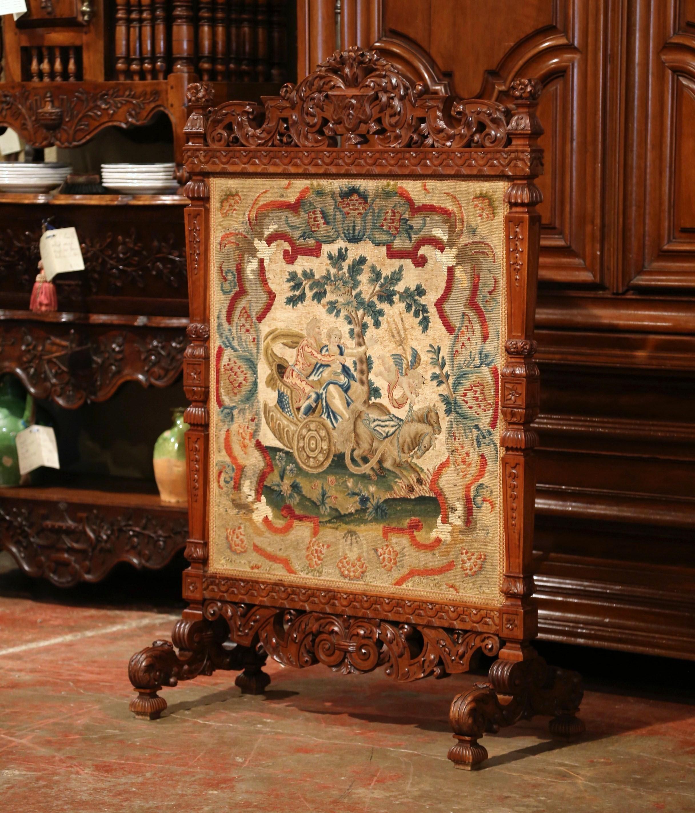 This elegant carved fruitwood screen was crafted in Southern France, circa 1860. The ornate, antique hand carved frame features a carved vase with foliage at the pediment with a carved shell motif at the base, and a colorful needlepoint tapestry