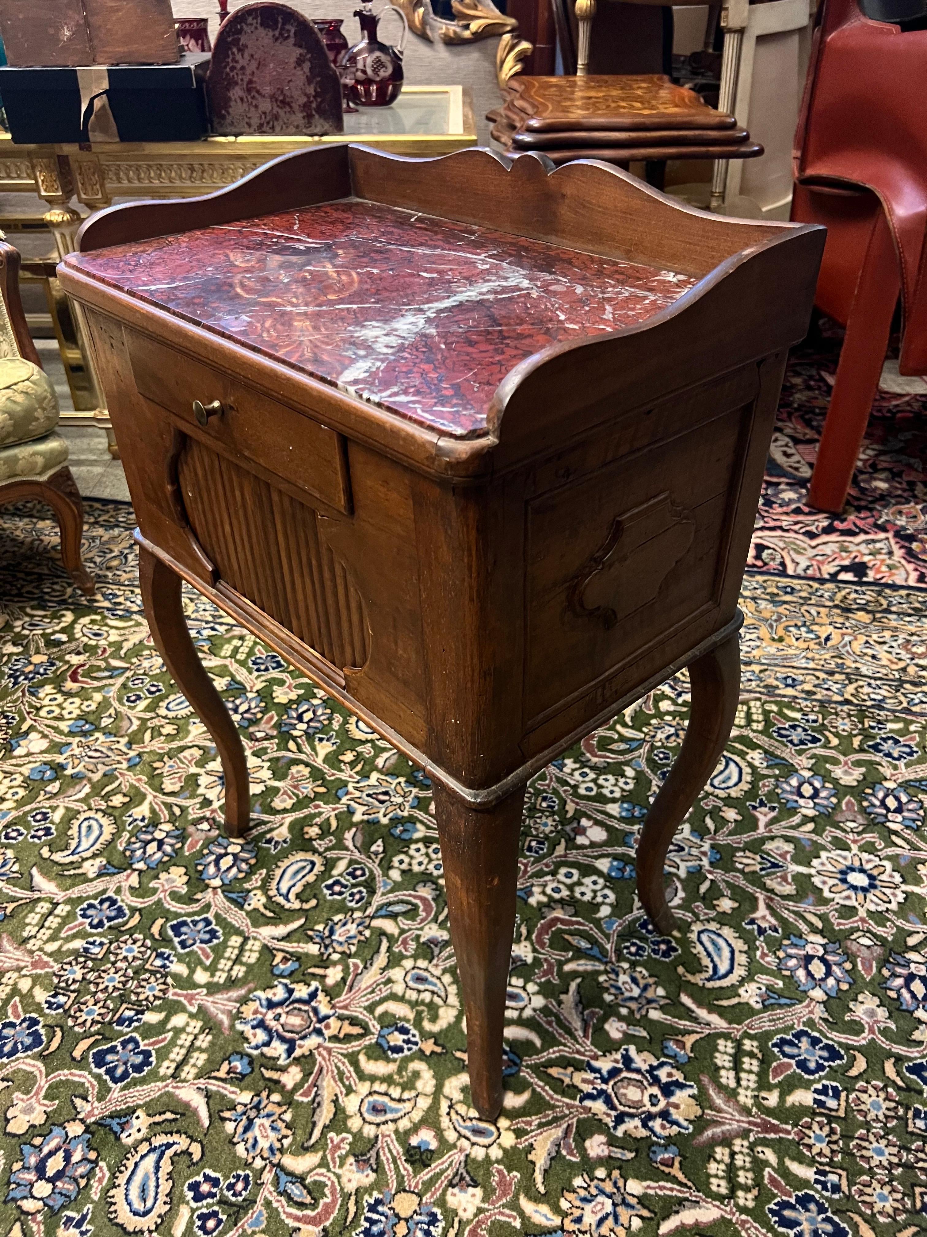 19th Century antique French hand carved walnut night stand raised on four curved legs with red marble top, one small front drawer and a front compartment with roller door. 
Made in France in the late 19th century, circa 1890