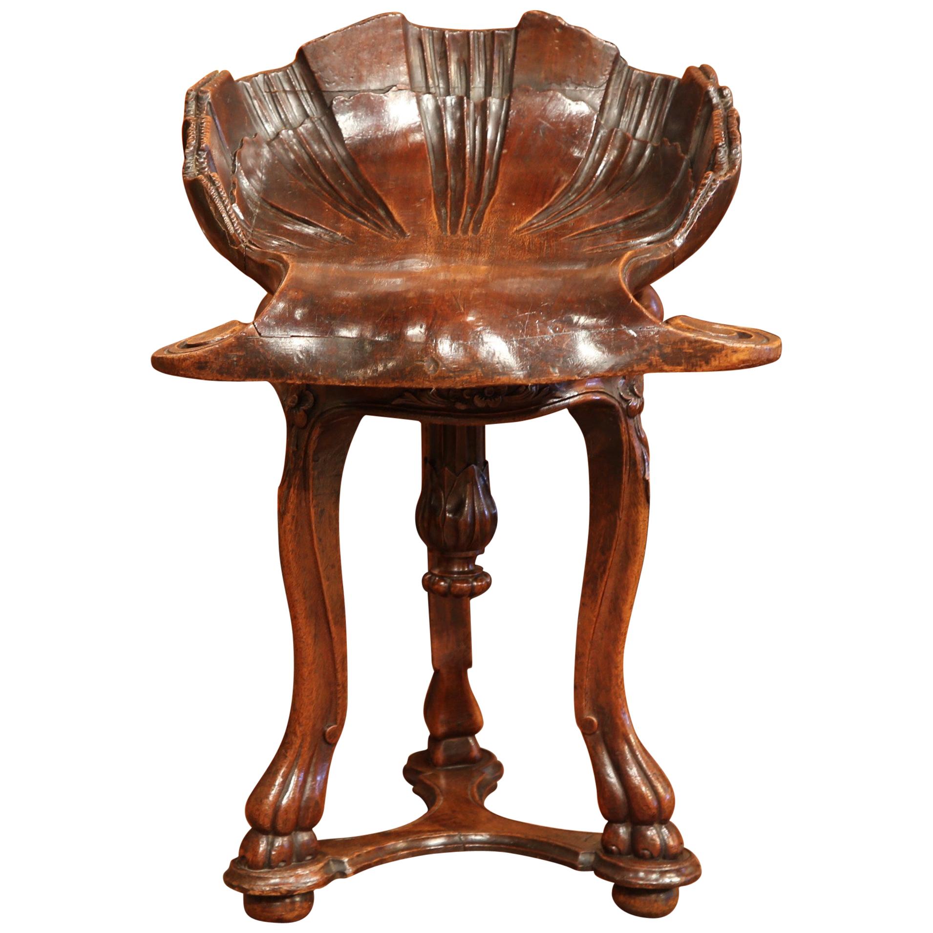 This carved antique fruitwood grotto stool was created in France, circa 1850. Perfect as a piano stool or simply a statement piece, the bench, stands on cabriole legs joined with bottom stretcher, and bun feet reminiscent of animal paws. The seat