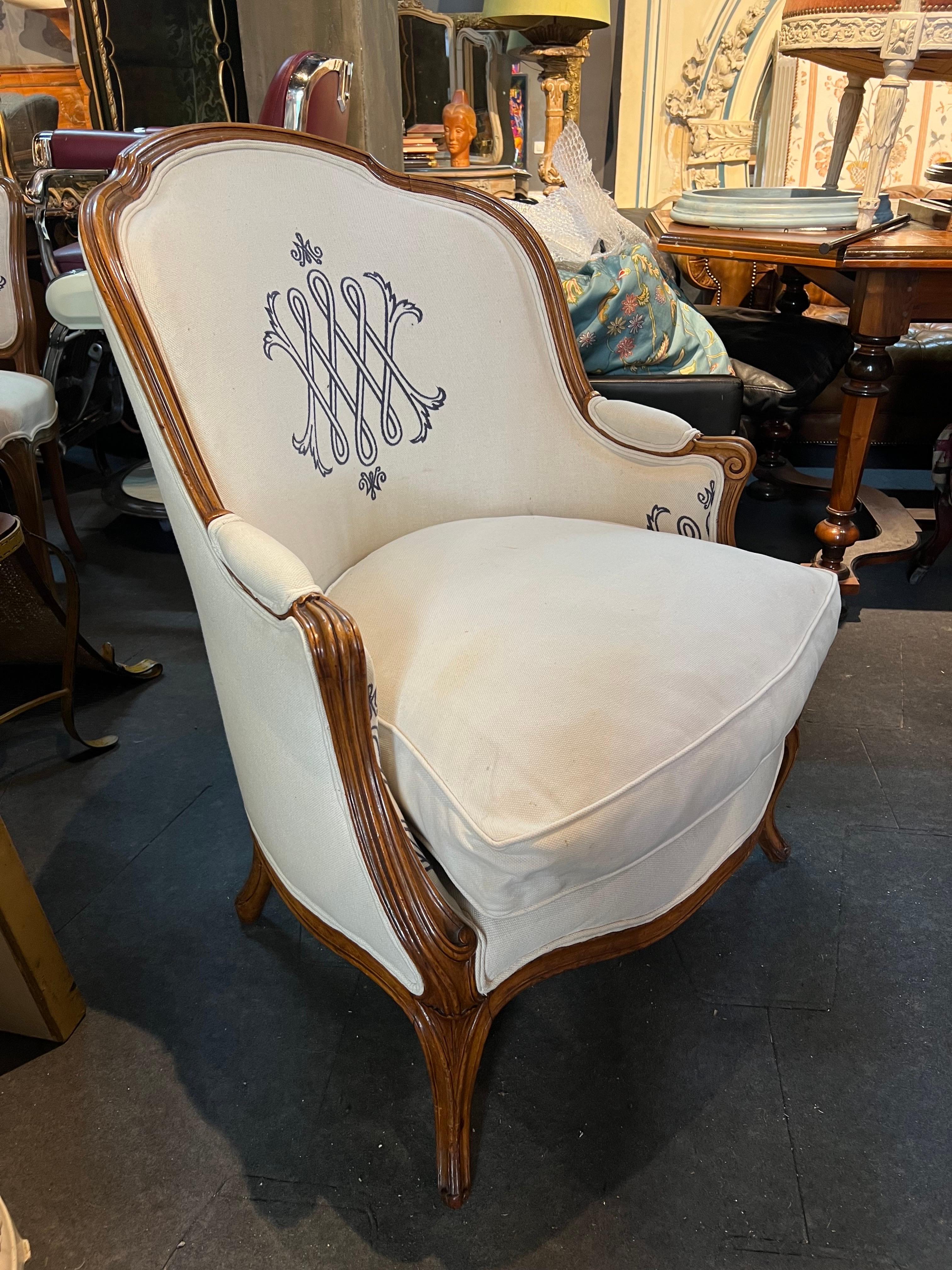 19th Century French hand carved walnut armchair with beige linen upholstery. There are two identical armchairs, but one of them has a damage on the inside part of the upholstery as it may be seen at the last photo. There are nice monograms on both