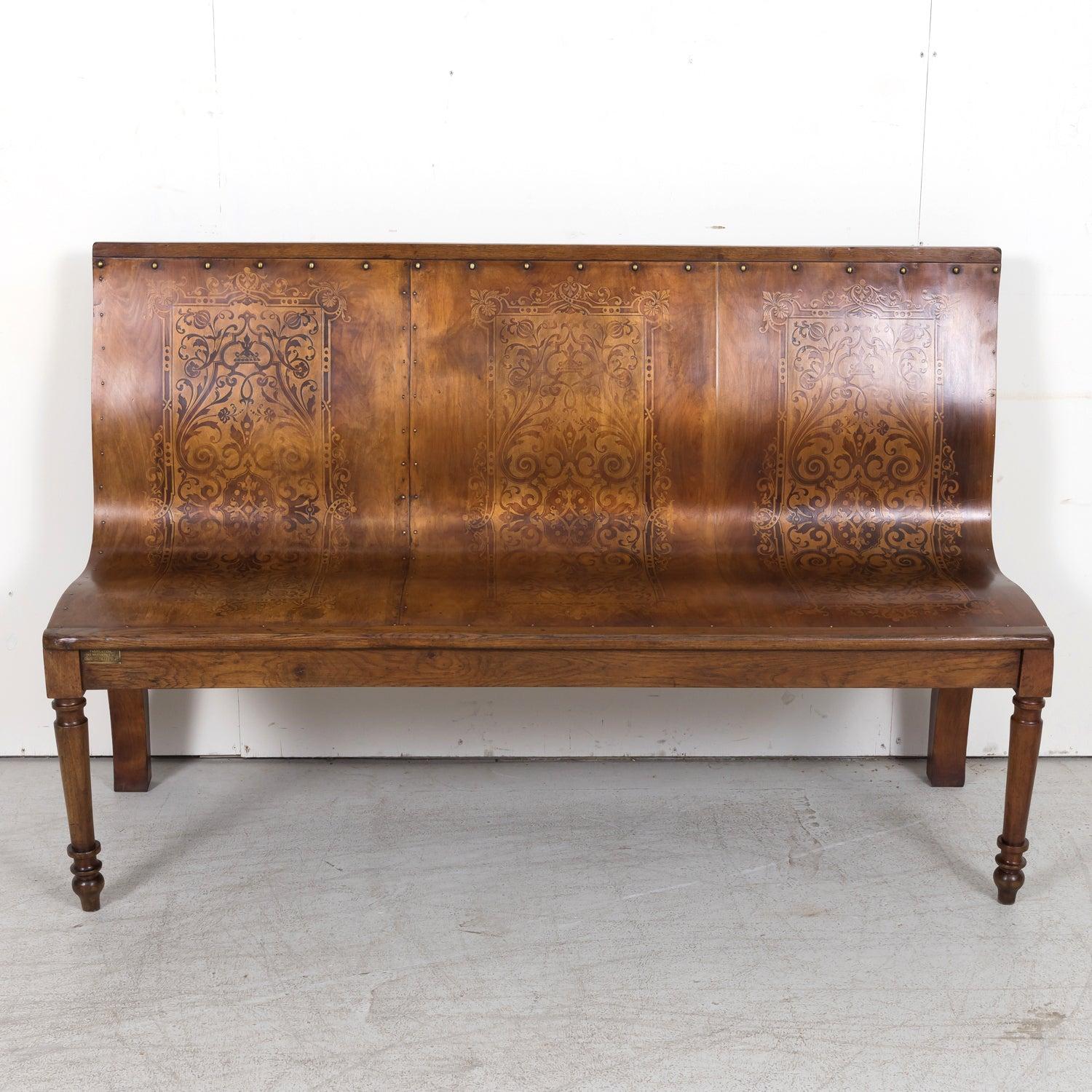 Questa straordinaria panca francese in legno di noce del XIX secolo, con tre posti a sedere, offre un significato storico e un'artigianalità senza tempo. Caratterizzata da un elegante intarsio in legno di frutta lungo la seduta e lo schienale,