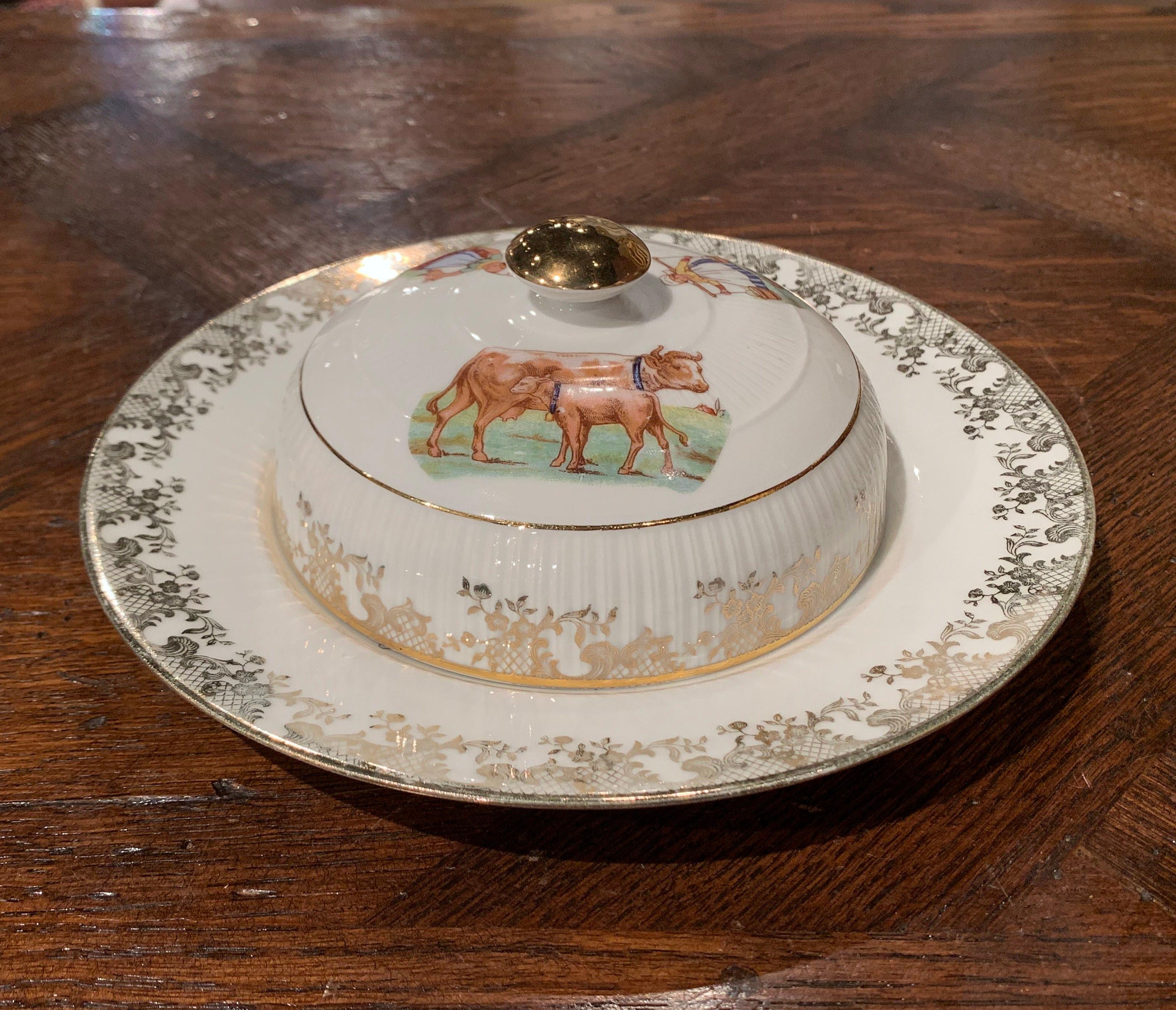 This antique butter or cheese dish was created in Limoges, France circa 1880. The two-piece porcelain plate and dome with knob are hand painted with pastoral scenes including farmer ladies and cows. Both pieces are in excellent condition with soft