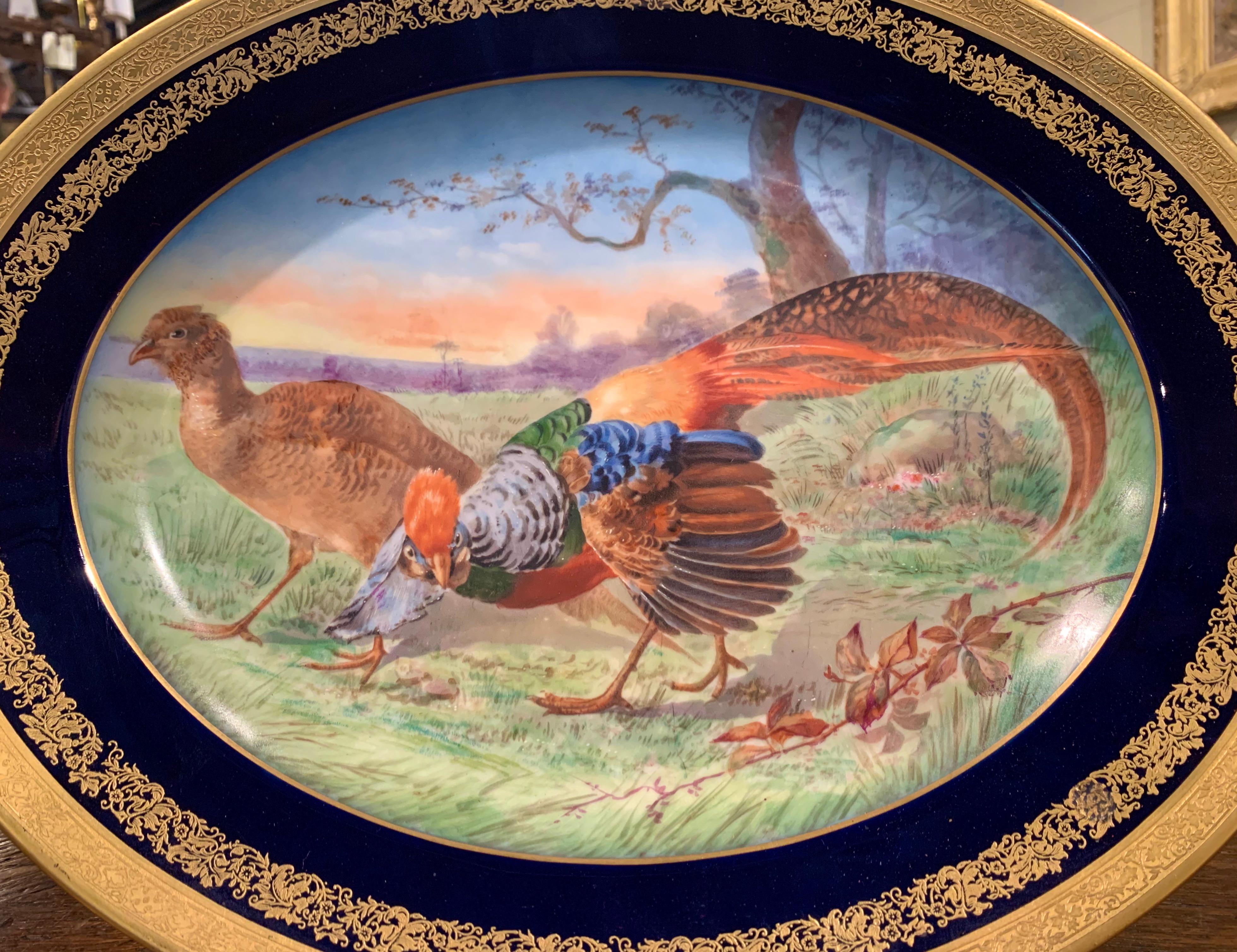 Decorate a wall or a bookcase with this Haviland Limoges style antique decorative wall platter. Crafted in Paris France, circa 1890 by Emile Bourgeois, the hand painted plate features two majestic colorful birds grazing in a field, the dish is