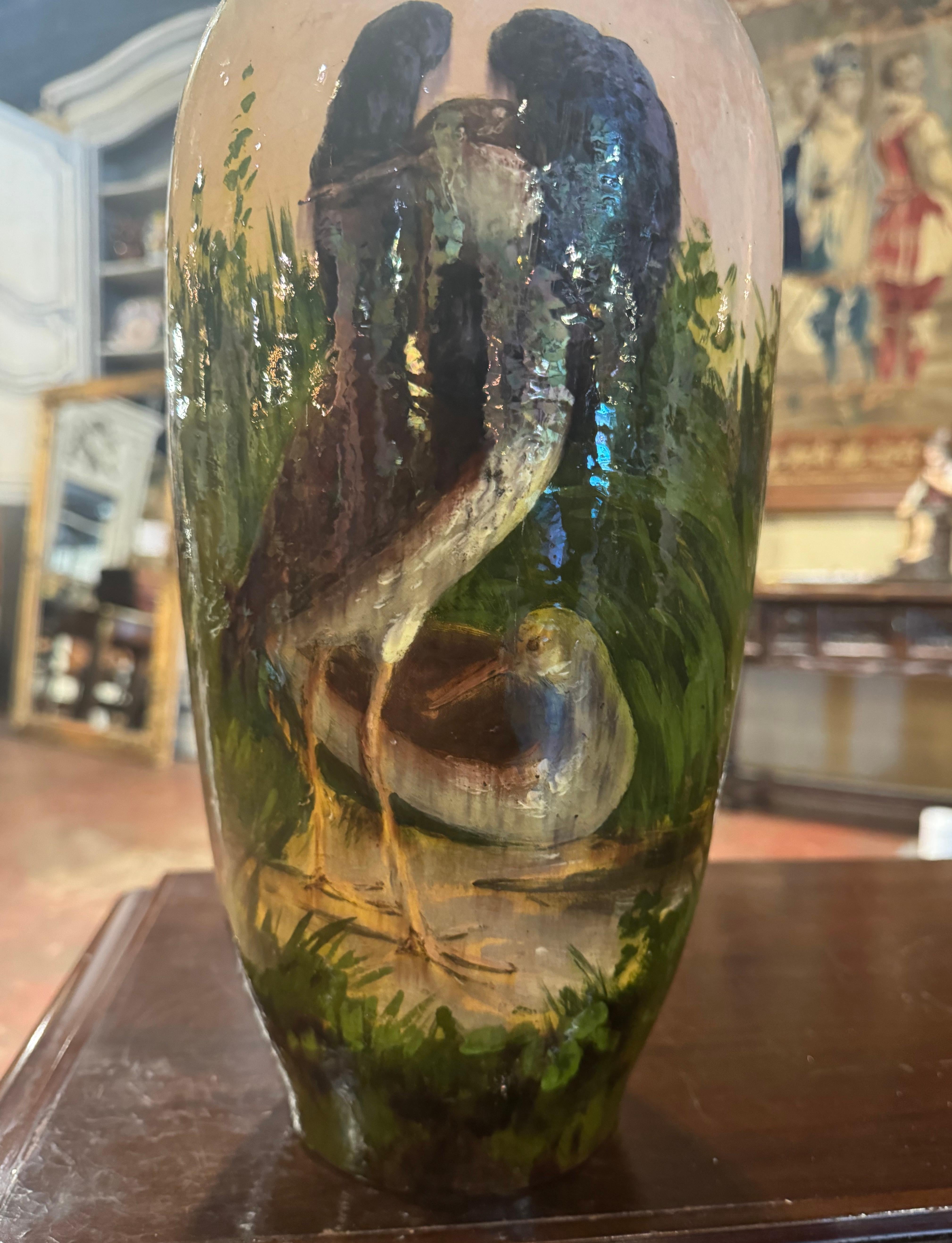 Questa colorata urna antica in maiolica è stata scolpita a Montigny sur Loing, in Francia, intorno al 1880. Alto e rotondo, il vaso in ceramica ha una forma alta ed elegante con un bordo svasato, che mette in mostra una splendida scena naturale