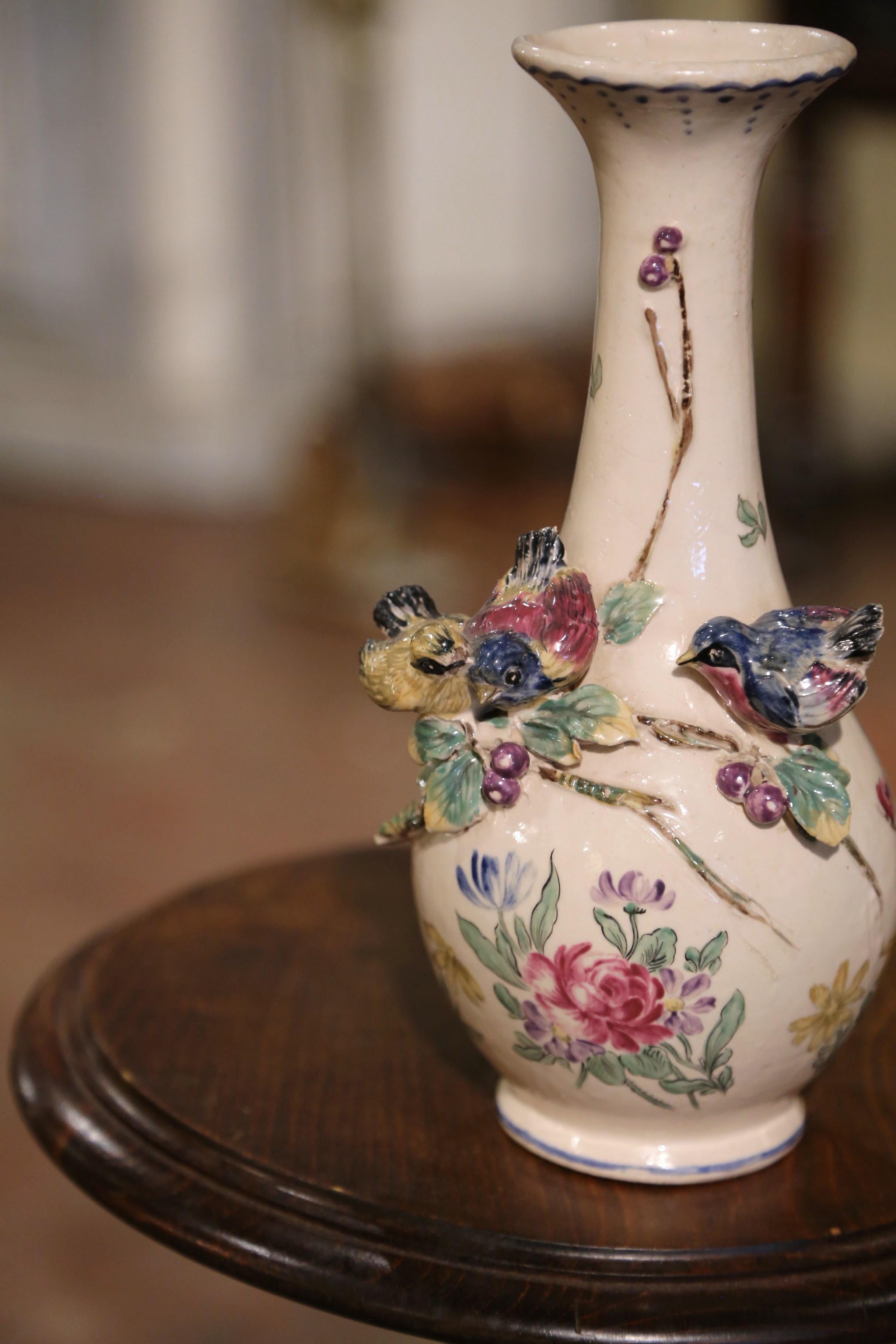 Ce vase antique en majolique colorée a été créé en France vers 1890. De forme ronde, ce vase décoratif en céramique présente des détails complexes, notamment des fleurs peintes et trois oiseaux en haut-relief perchés sur des branches. Le vase peint