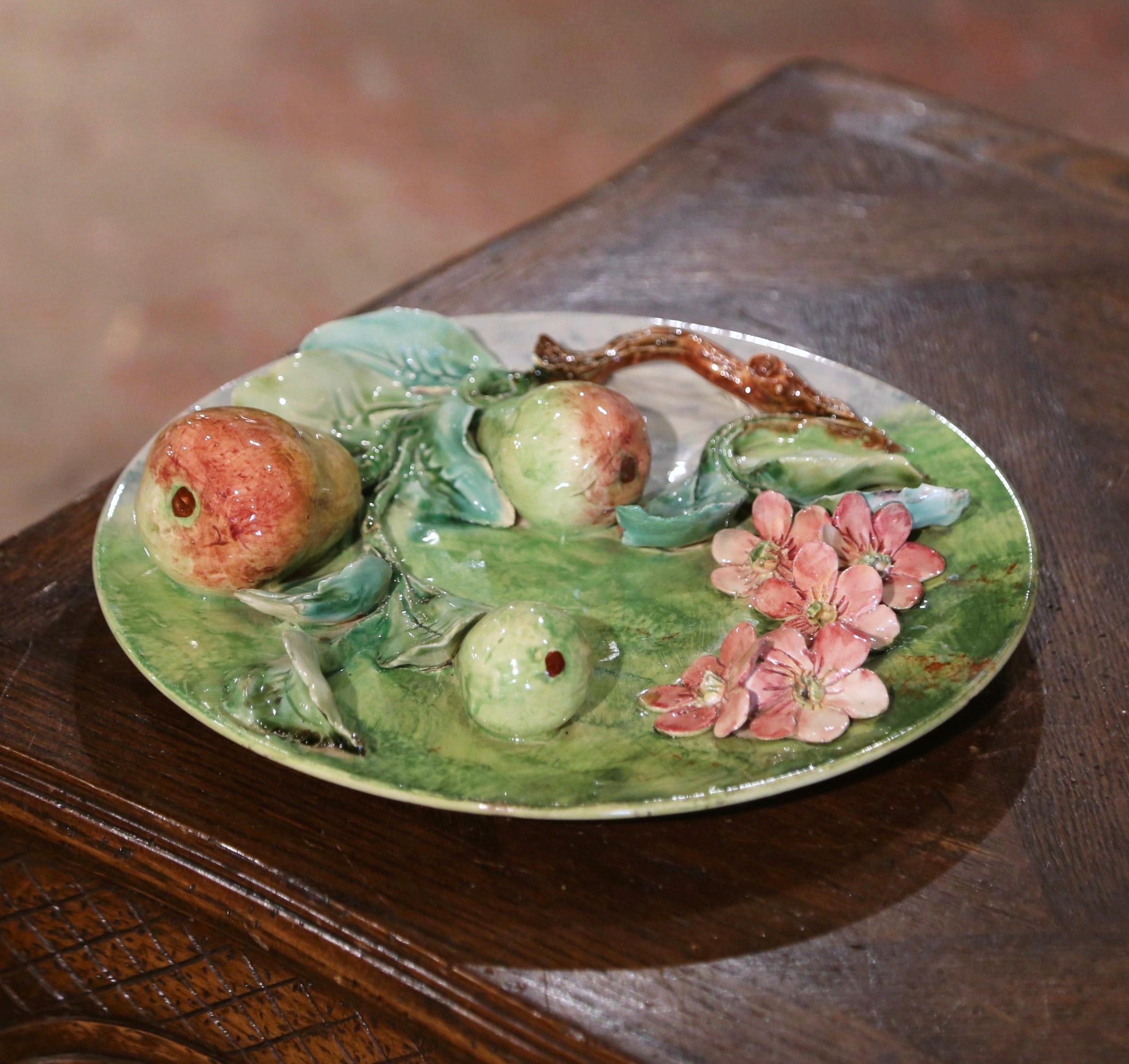Ajoutez de la couleur au mur de votre cuisine ou à l'étagère de votre salle à manger avec ce magnifique plat mural en majolique ancienne. Fabriquée en France, vers 1880, l'assiette présente un motif sculptural de fruits en haut-relief qui comprend