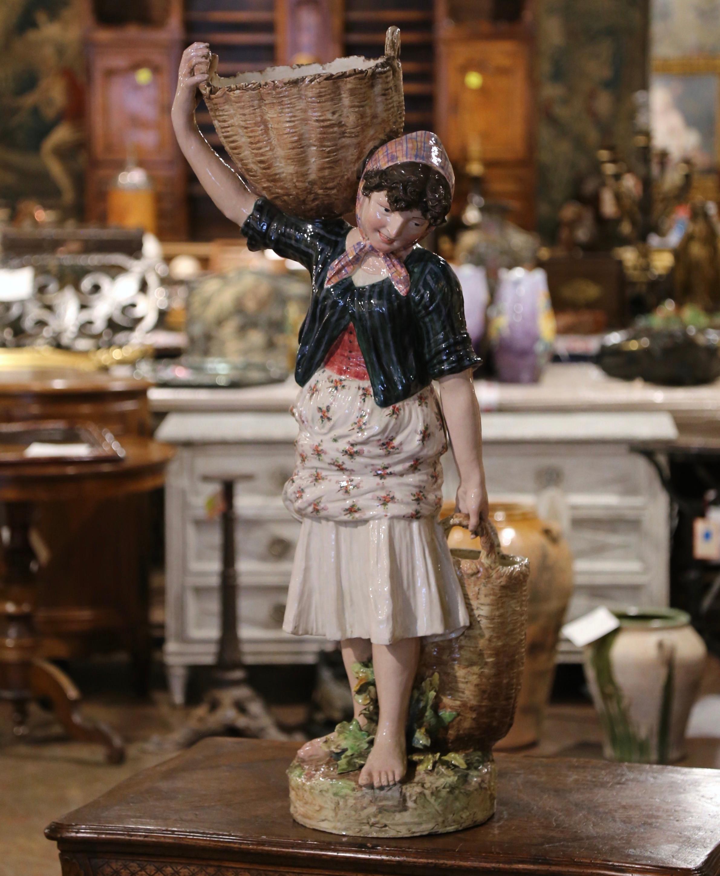 Decorate a kitchen counter with this large and elegant antique figurine. Created in France circa 1880 and attributed to Massier, the large barbotine statue depict a peasant woman dressed in traditional clothing. The young girl is shown wearing a