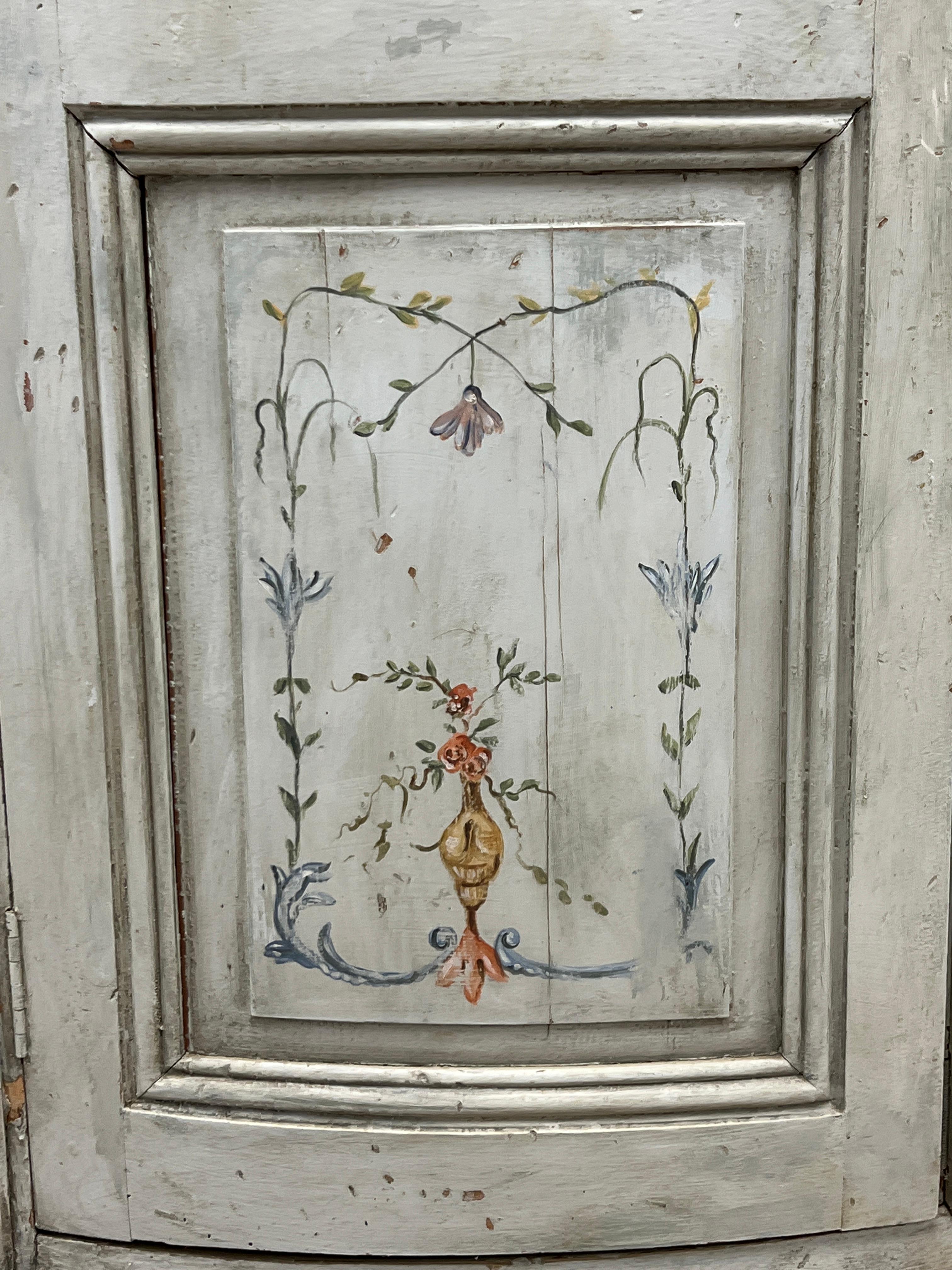 Featuring a charming French hand-painted bow front corner cupboard in the Gustavian style. The right door has an operational fitted key that operates. There is a small spring latch on the interior of the left door. The exterior door panels are