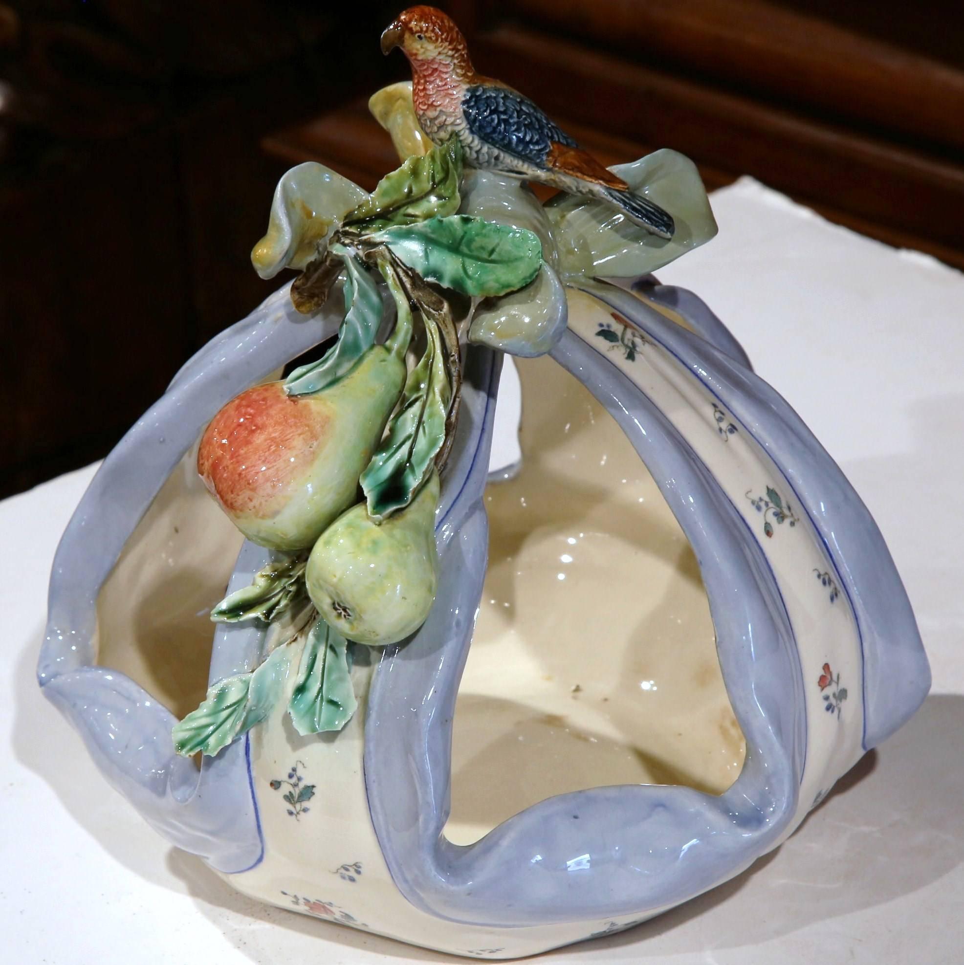 Beautiful antique Majolica centrepiece from Provence, France; crafted circa 1880, the ceramic fruit basket is shaped as center bow decorated with flowers. The top of the basket features two pears with leaf decor and a colorful bird standing at the