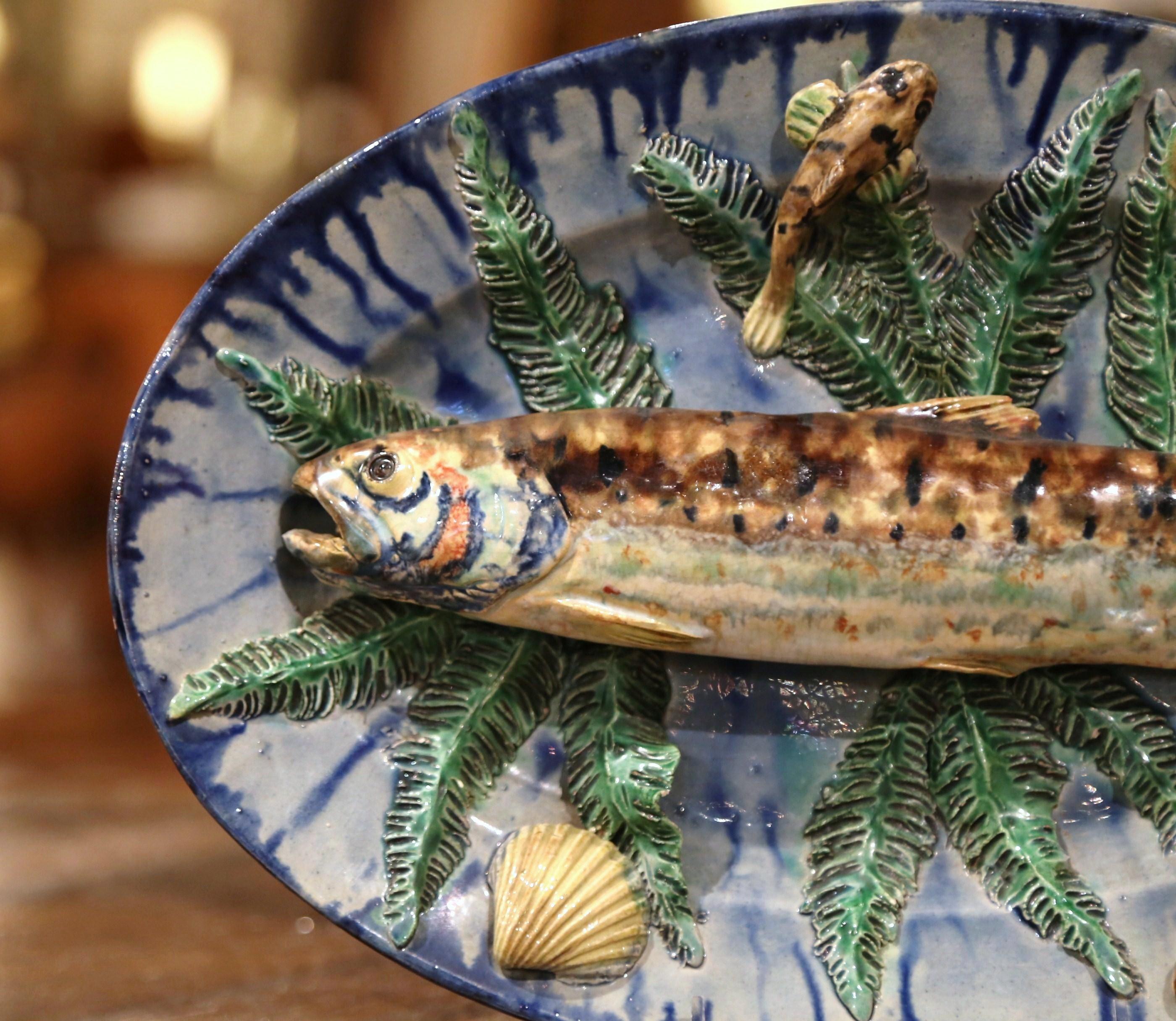 Decorate a wall or a shelf with this colorful antique Majolica fish platter. Crafted in France, circa 1880, the oval, ceramic plate features high relief sculptures of water creatures in the manner of Palissy. The realistic still life arrangement
