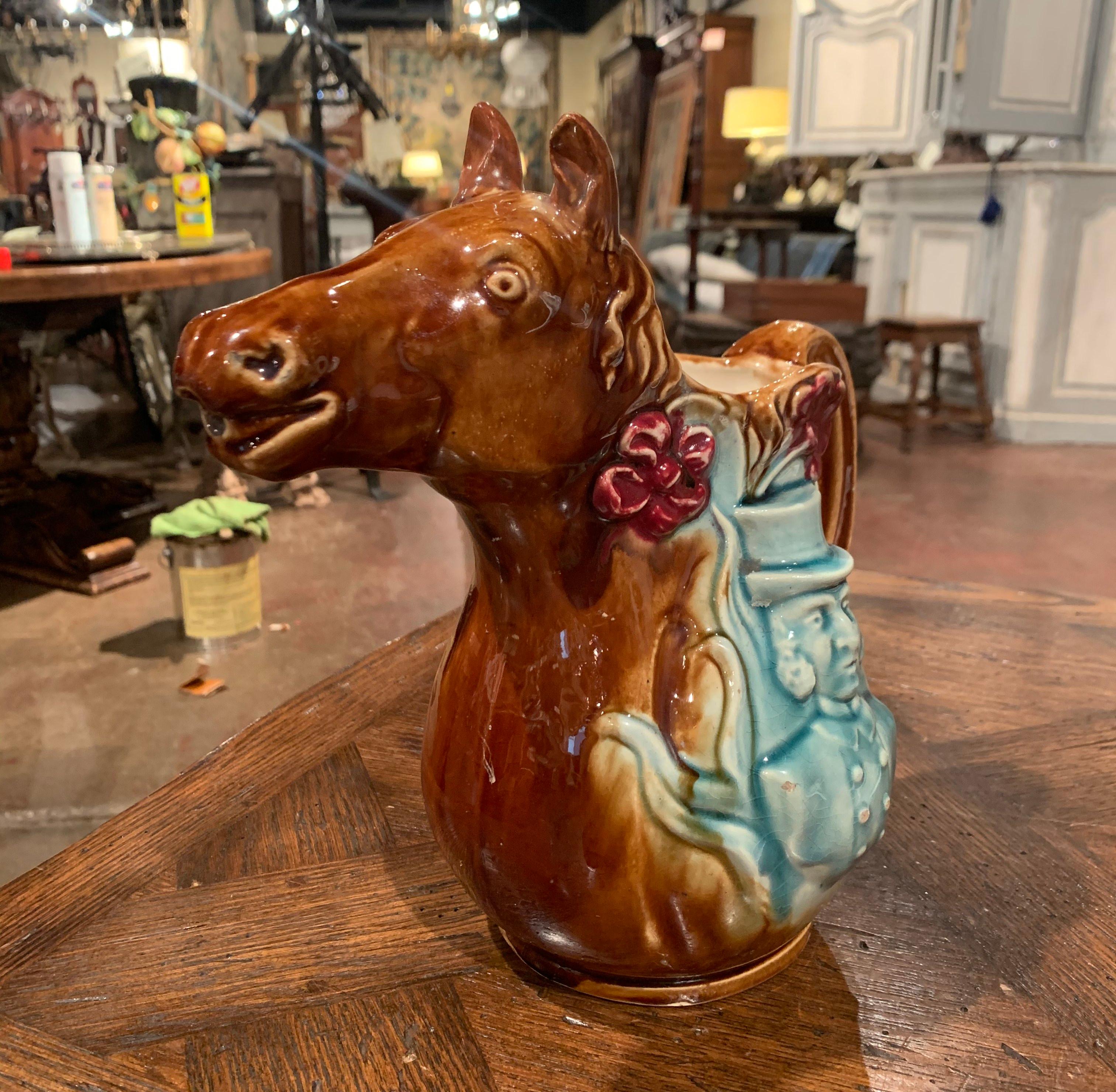 This colorful, antique water pitcher was crafted in Northern France, circa 1880 in the manner of Onnaing style. The jug with handle features a horse sculpture with a cab-driver on one side and a jockey on the other. The figure has wonderful facial