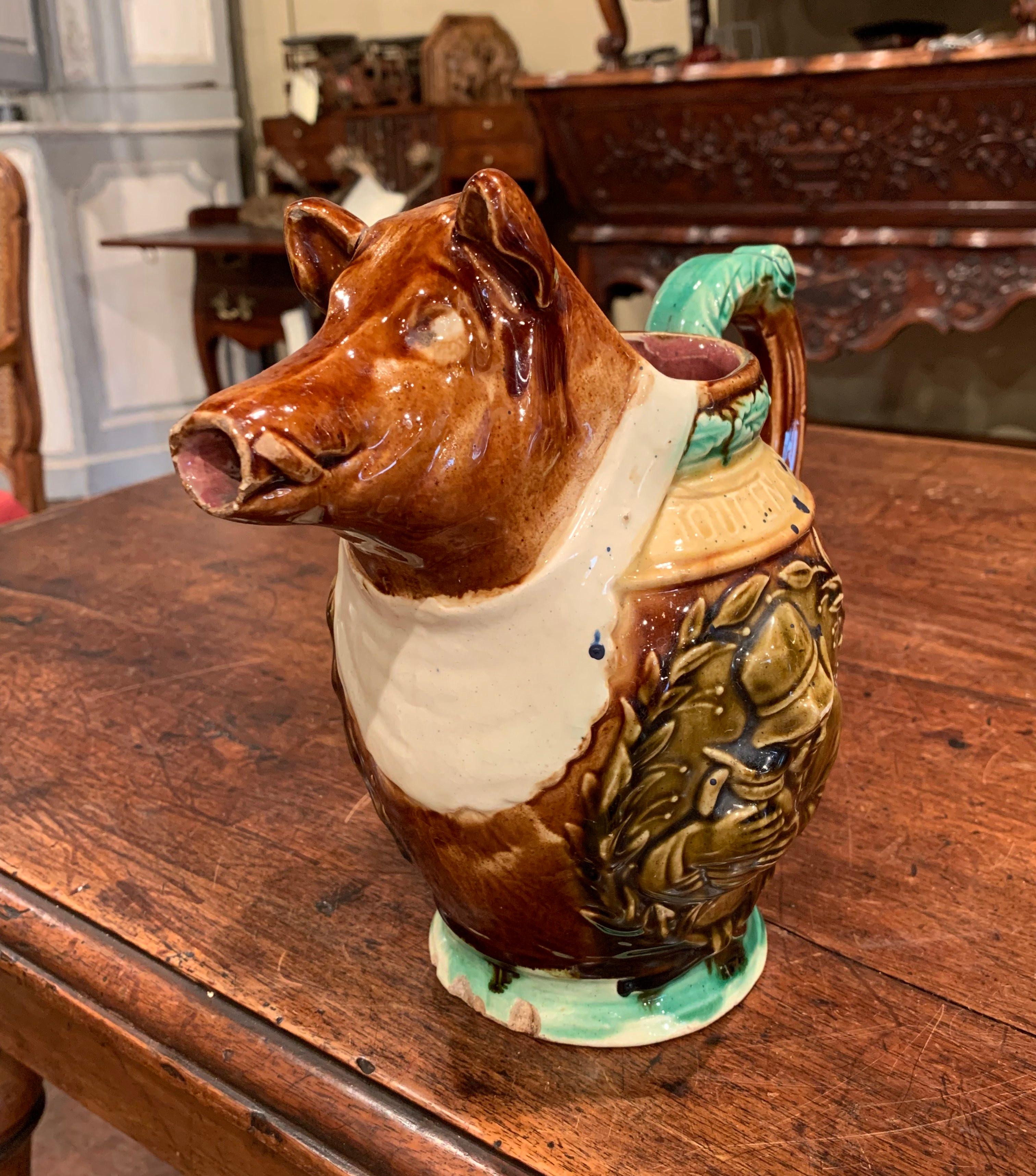 Porcelain collectors will love this colorful, Majolica water pitcher in the shape of a wild boar. Sculpted in France, circa 1890, the artful ceramic jug features a boar sculpture wearing a bib emblazoned with the words 