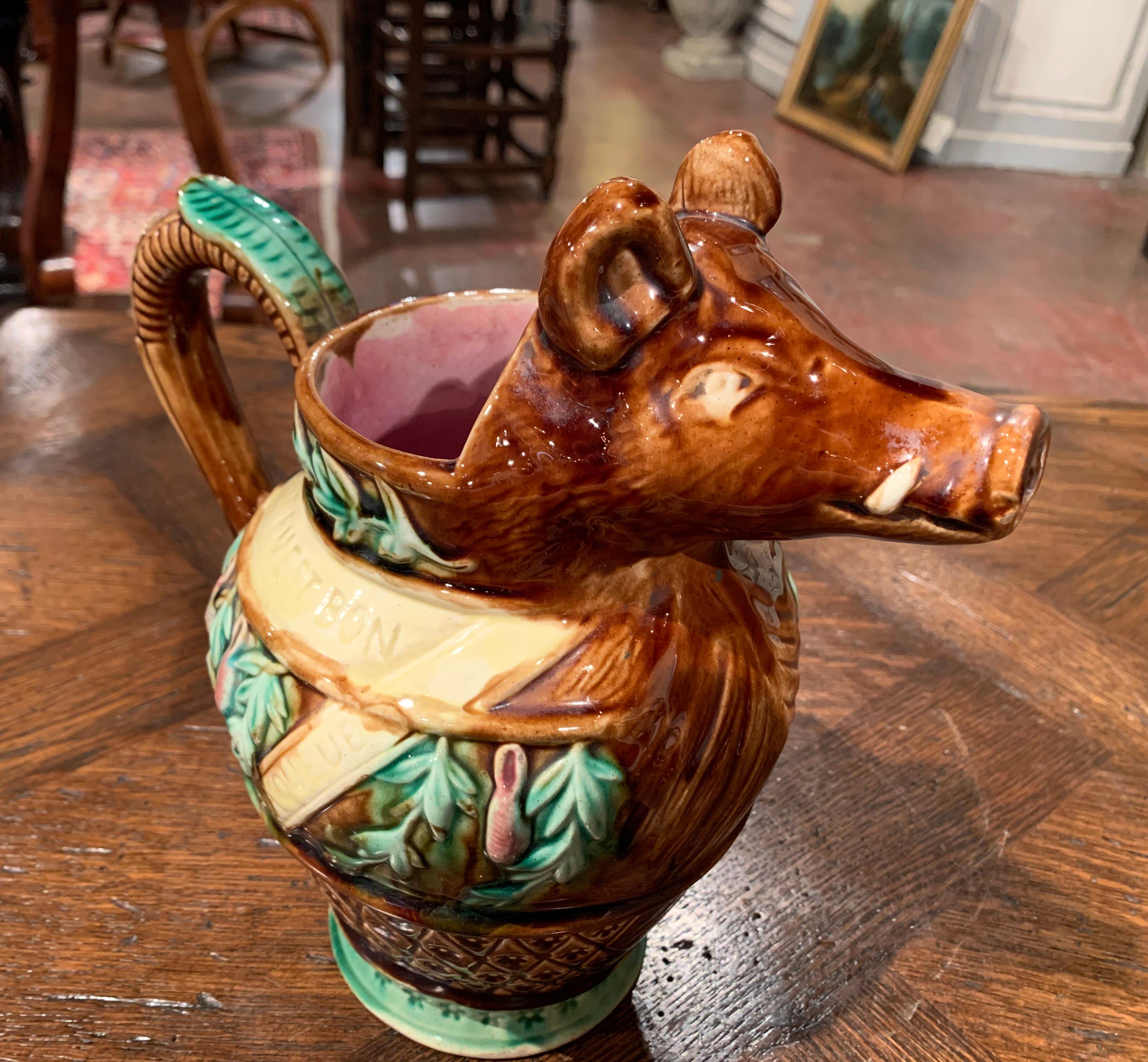Porcelain collectors will love this colorful, Majolica water pitcher in the shape of a warthog. Sculpted in France, circa 1890, the artful ceramic jug features a boar sculpture wearing a bib emblazoned with the words 