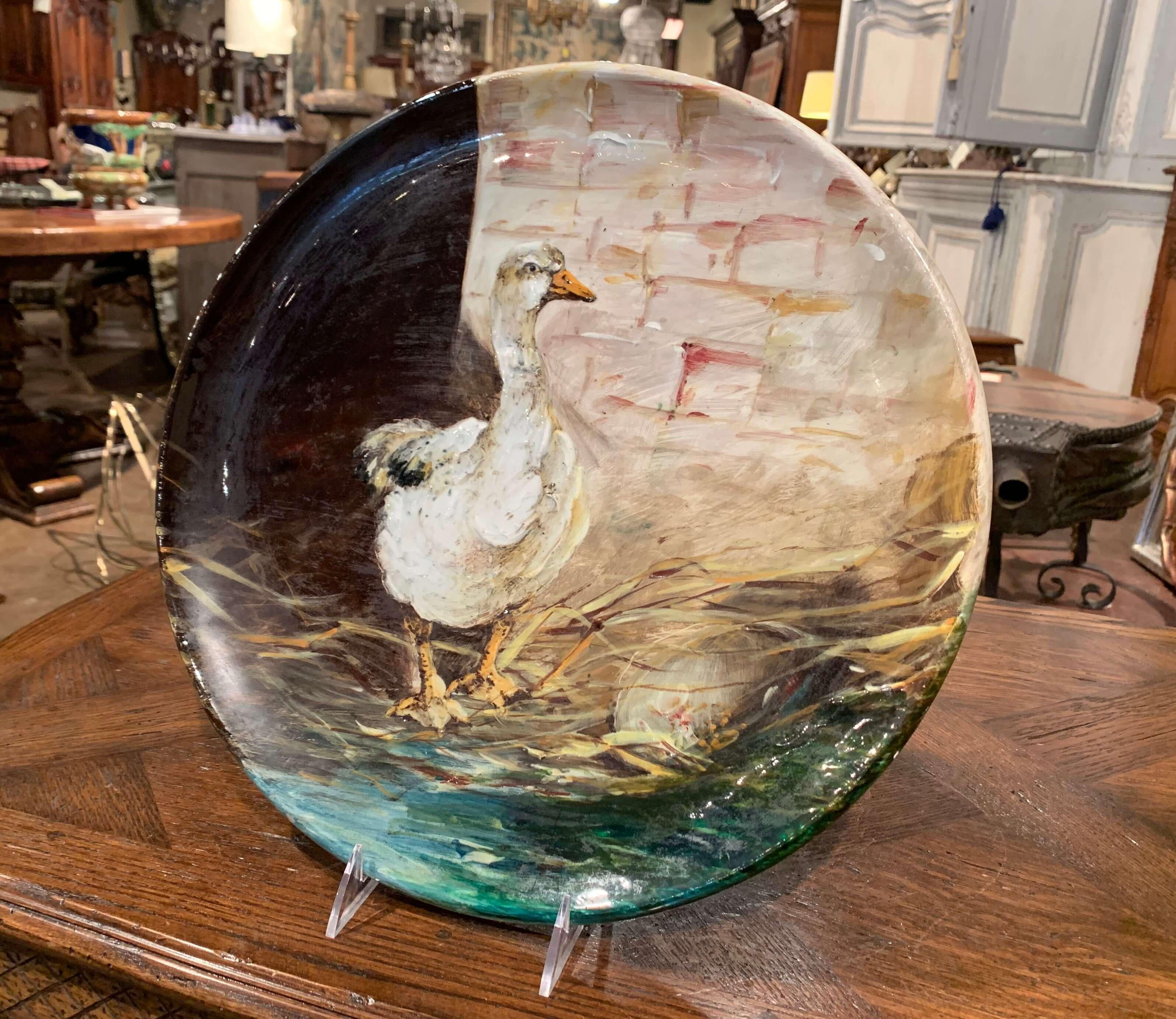 This elegant Majolica platter was created in Southern France by Massier, circa 1890. Round in shape, the antique ceramic plate is beautifully hand painted featuring a standing duck in a barn. The planter is in excellent condition with rich colors in