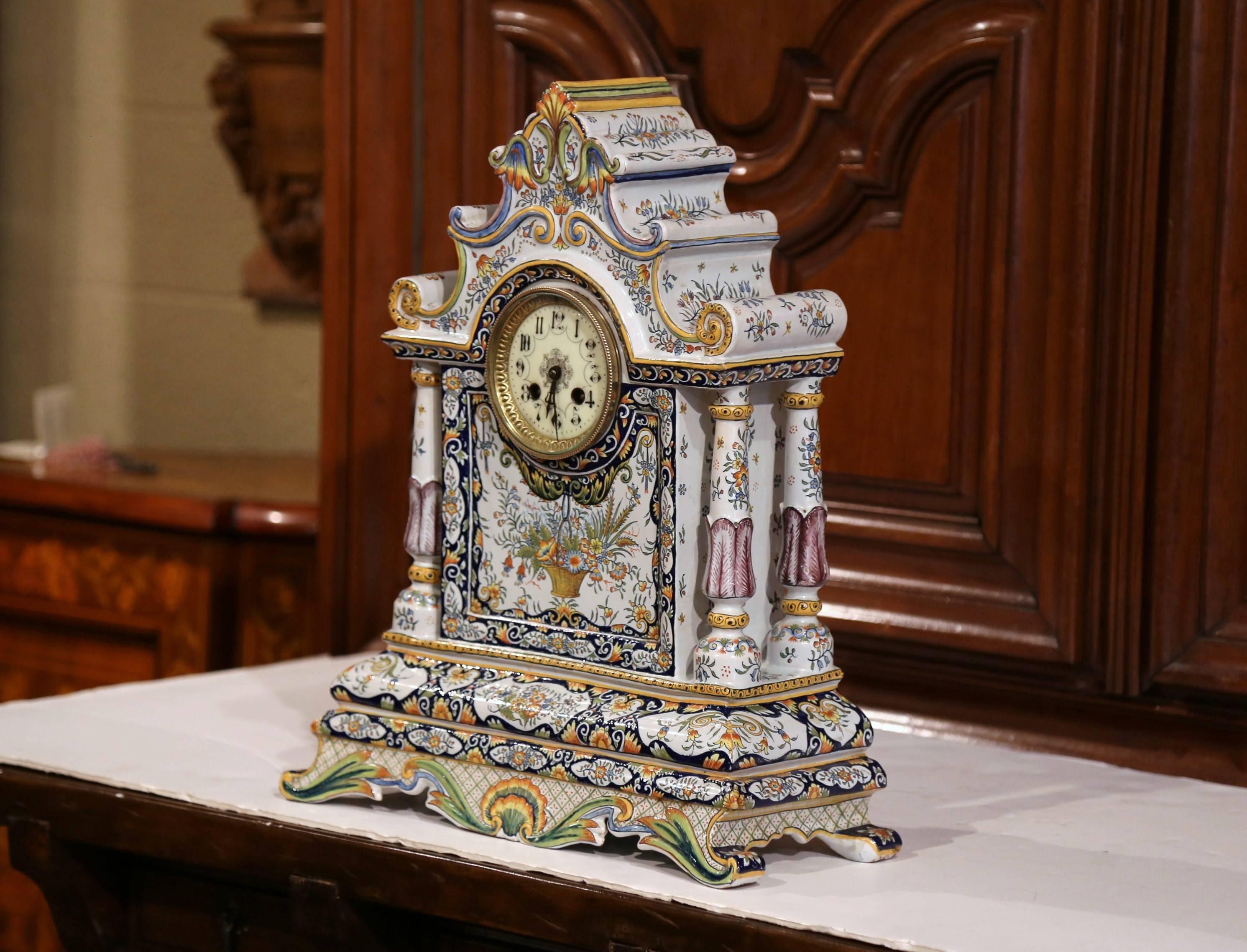 This elegant antique clock was crafted in Normandy, France, circa 1870. The colorful mantel clock sits on four curved feet with shell and leaf decor. The porcelain timepiece features an intricate top with curved shapes, a center enamel clock face,
