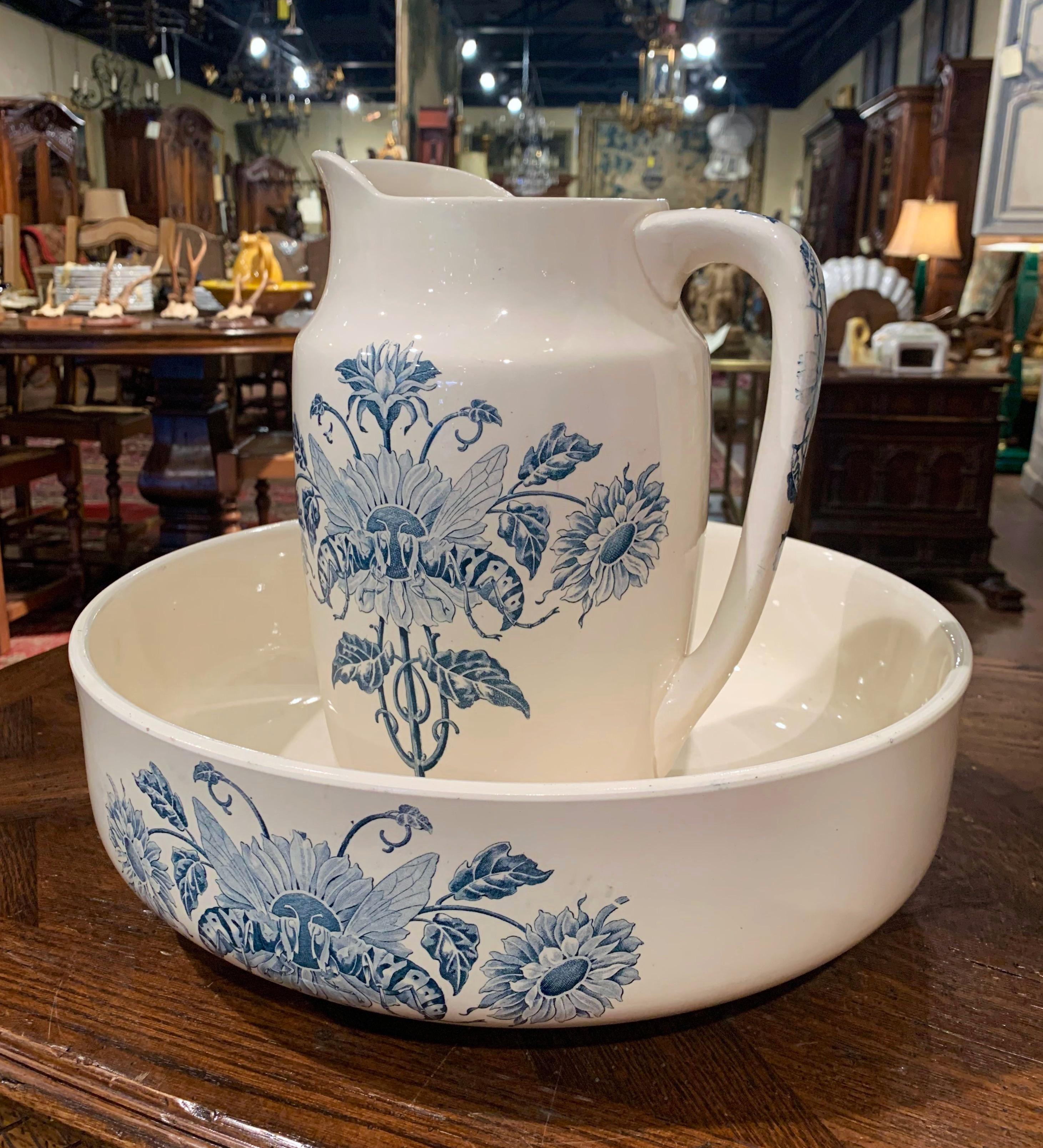 This elegant antique water pitcher with matching bowl were crafted in Longchamp France, circa 1860, typically used to freshen up in the morning, the ceramic set is hand painted with blue and white floral and leaf motifs embellished with two large