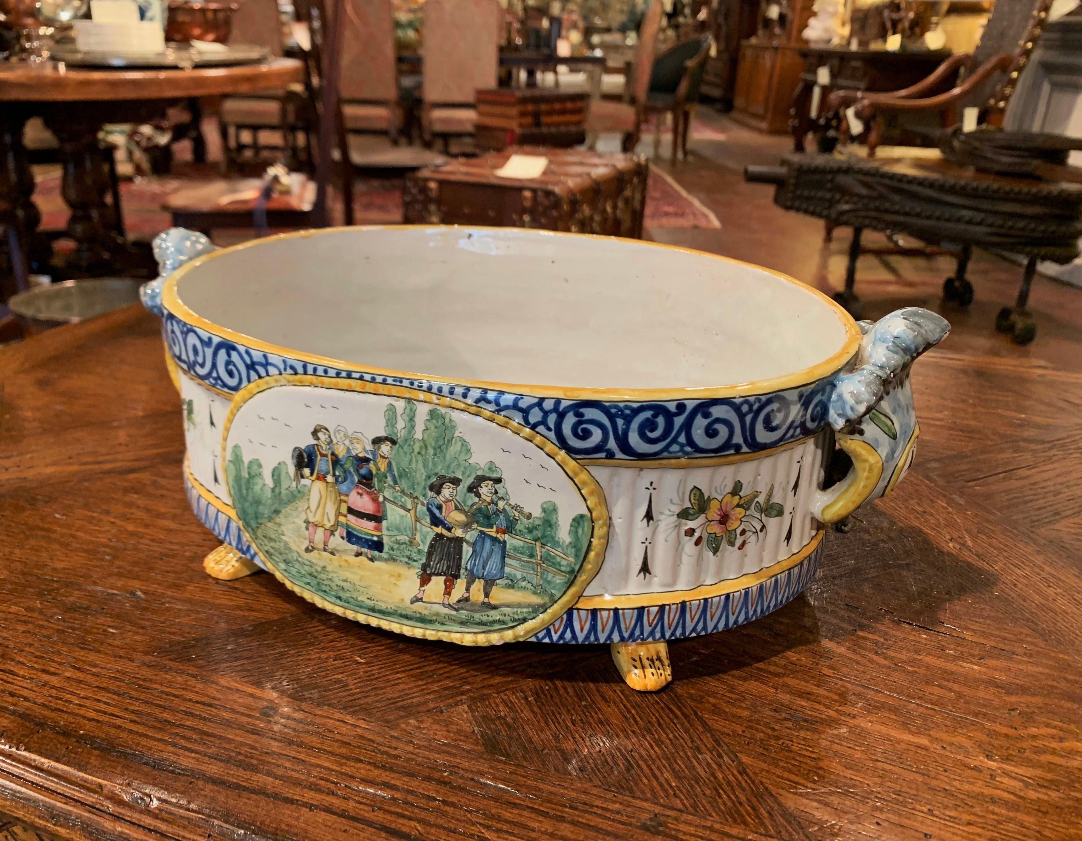 Complete your faience collection with this colorful antique cachepot from Brittany. Crafted in Quimper, France, circa 1880 and oval in shape, the jardinière with curved side handles stands on four paw feet; on each side, the ceramic planter features