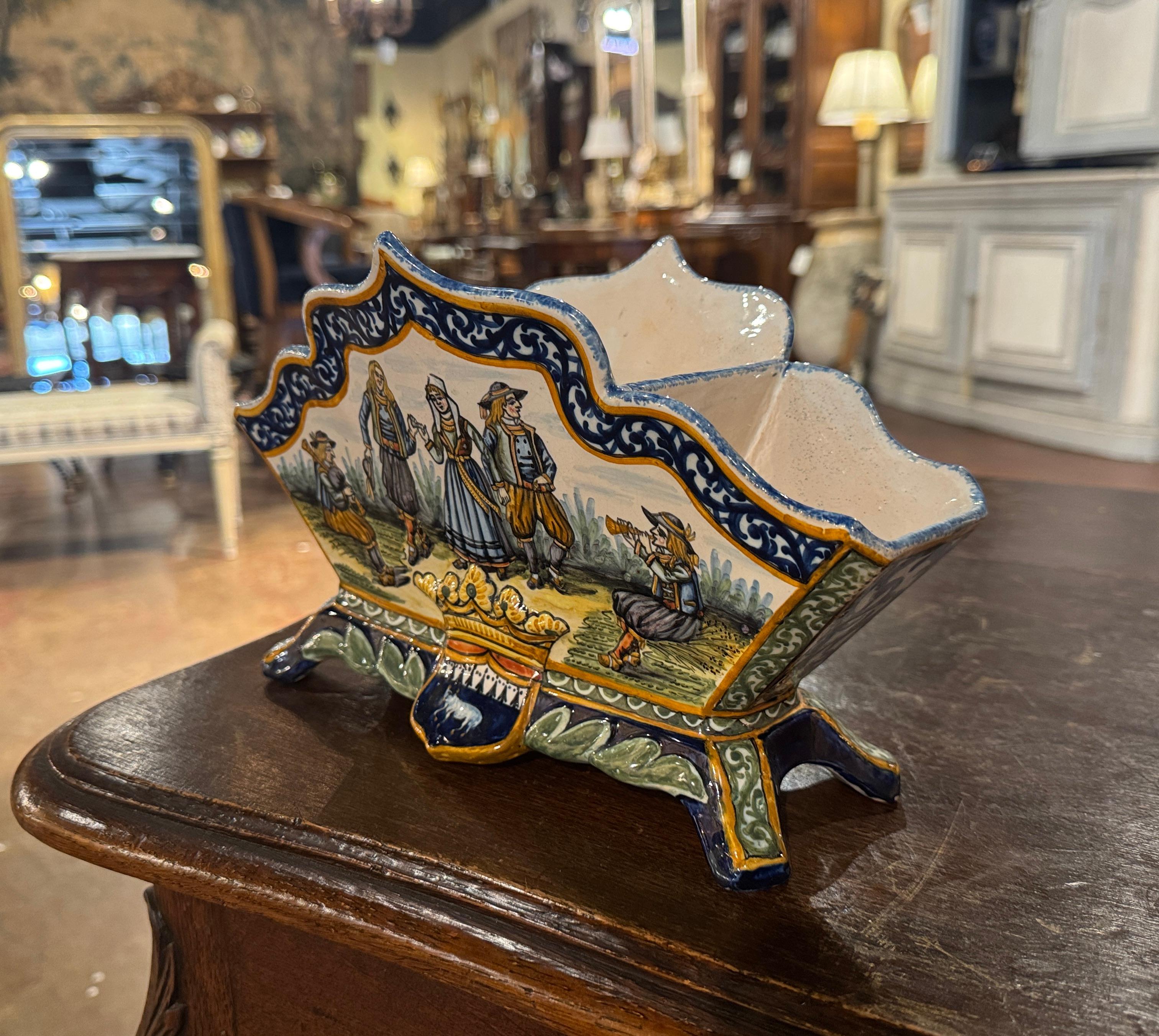 Decorate a buffet or table with this colorful antique faience jardiniere. Crafted in Brittany, France, circa 1880, the planter stands on four small feet over a scalloped apron decorated with a family crest in the center. The hand painted vessel with