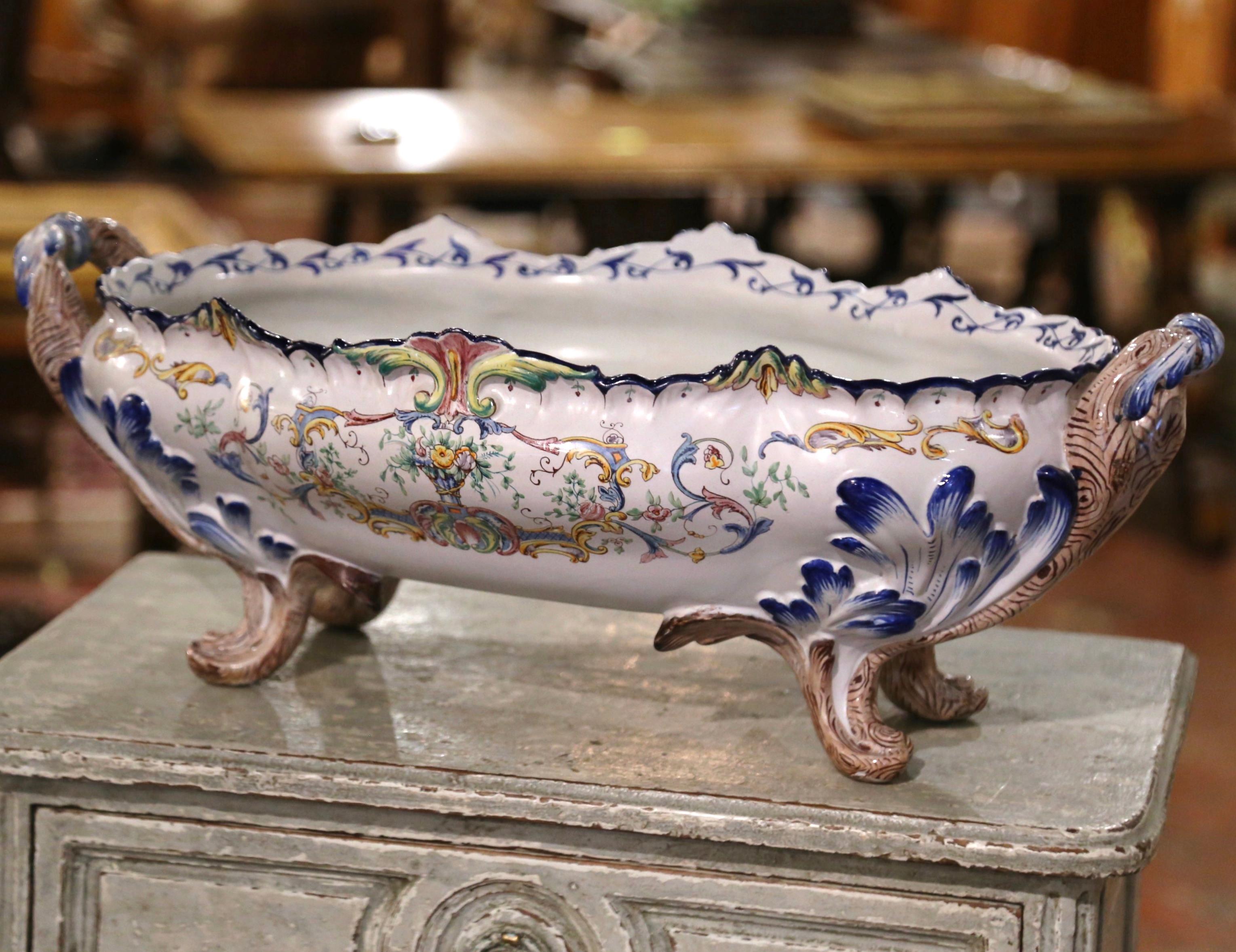 Crafted in Normandy, France, circa 1890, the large ceramic bombe planter sits on four scroll feet decorated with acanthus leaves. The shallow, detailed planter dressed with elegant scrolled rope-form side handles, features a scalloped rim around the