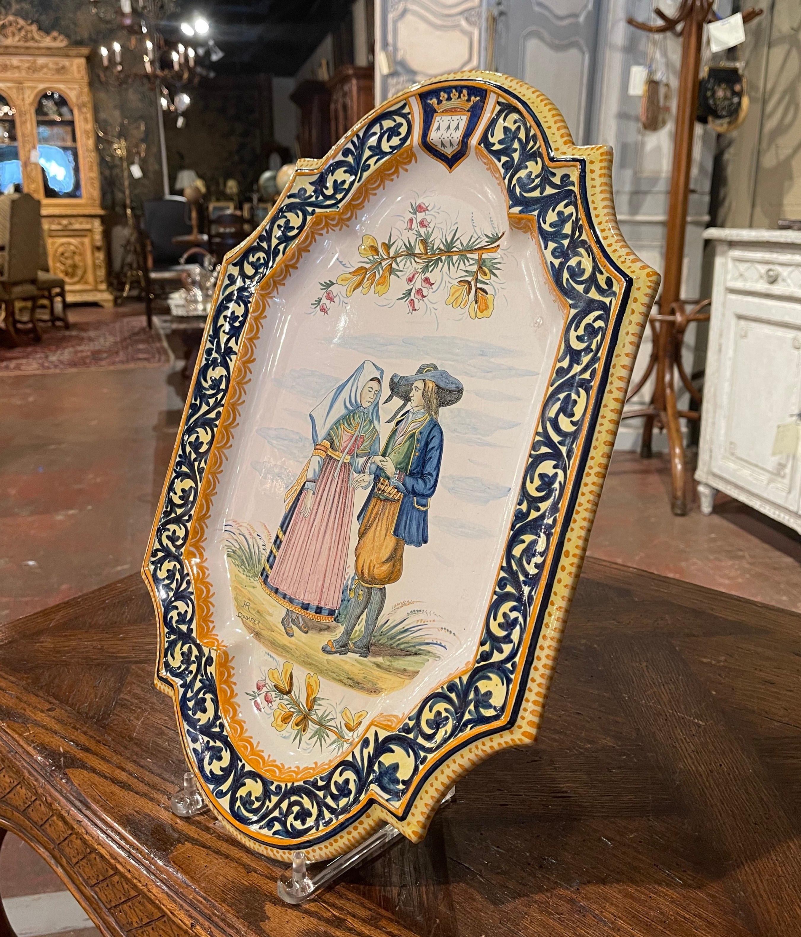 Decorate a wall or a shelf with this important antique platter. Created in Brittany, France circa 1895, the large hand painted ceramic plate depicts a Breton couple dancing in traditional costumes. The oval, porcelain platter is decorated with a