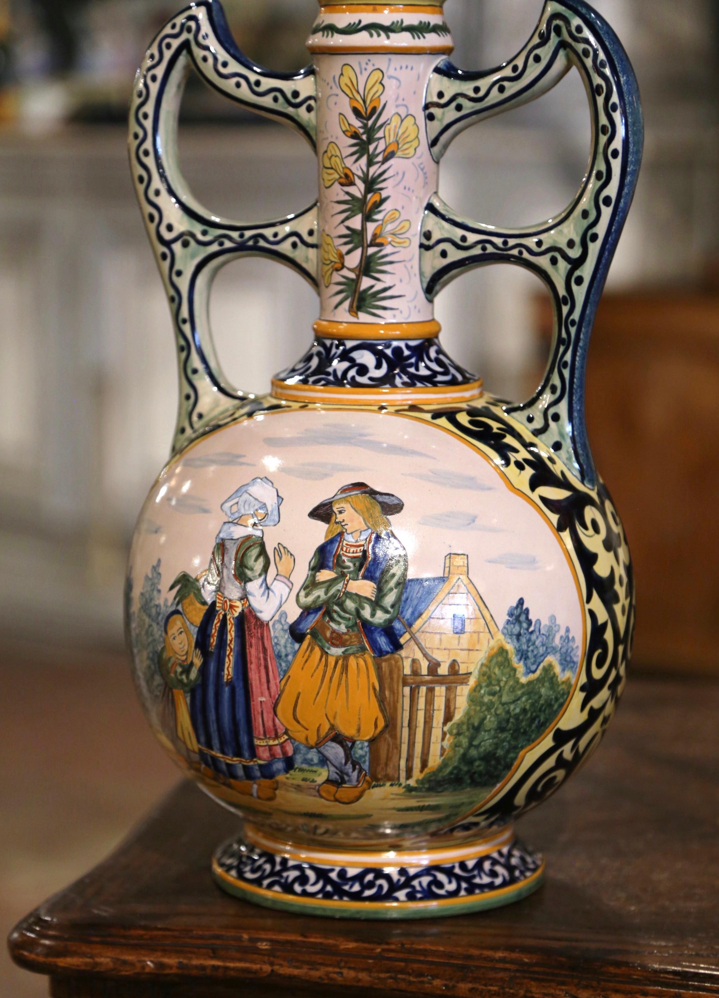 Decorate a mantel or table with this colorful antique faience vase. Crafted in Brittany, France, circa 1880, the large urn-shape vessel is round in shape, and dressed with large scrolled side handles over a long neck. The hand painted vessel