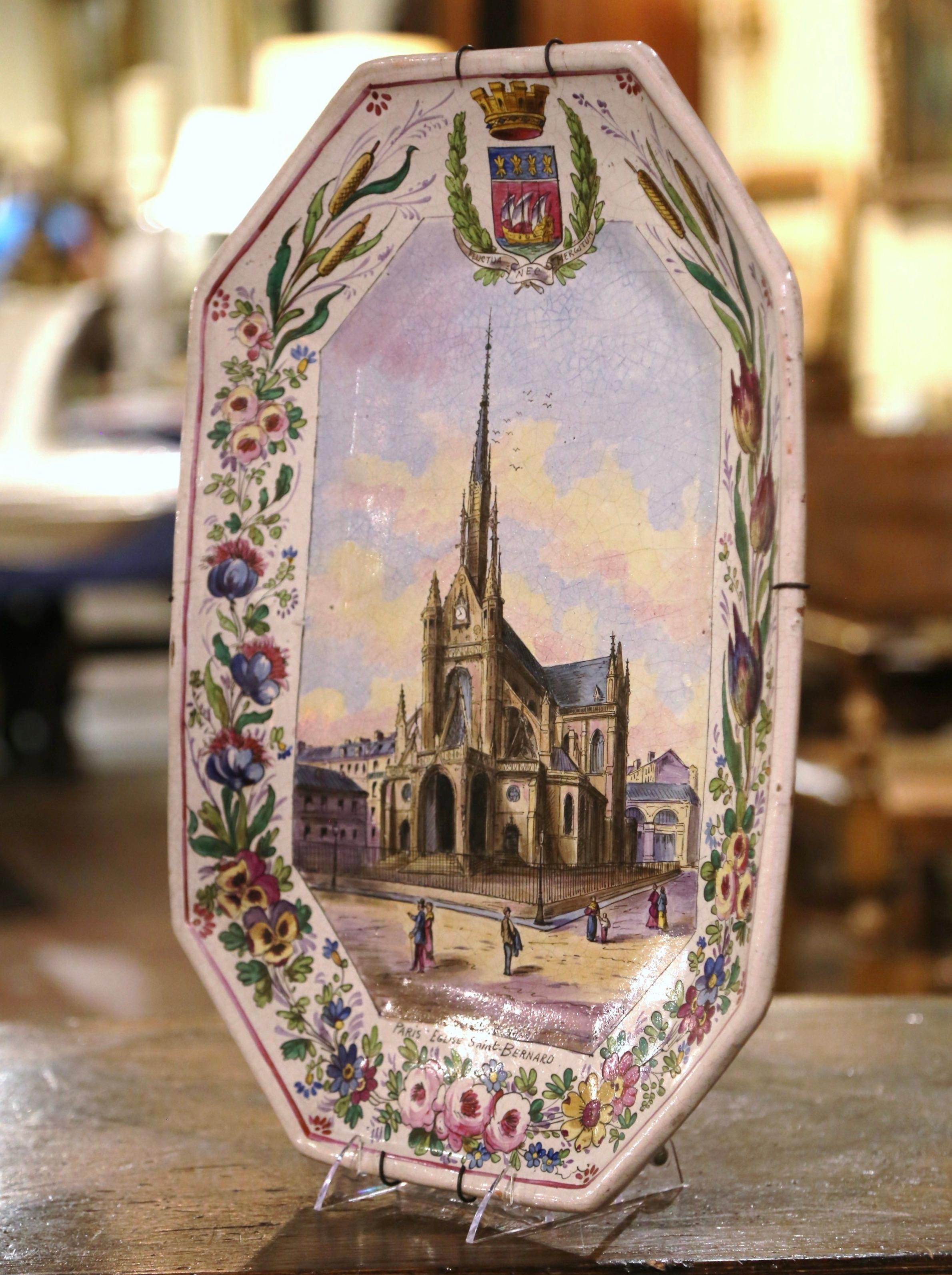 Decorate a wall or a shelf with this important colorful antique platter. Created in France circa 1895, the large hand painted ceramic plate depicts the magnificent Eglise Saint-Bernard, or The Church of St. Bernard in Paris. The painted scene is