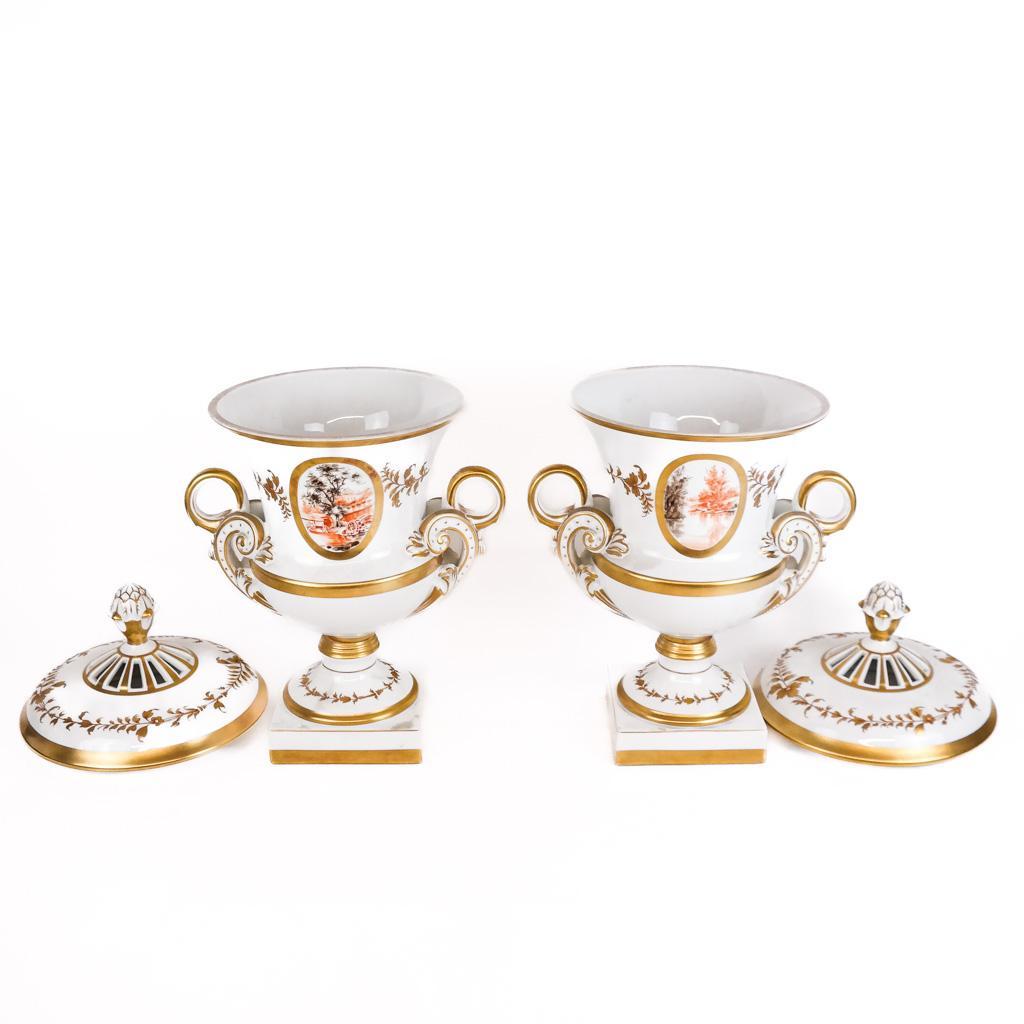 Découvrez une captivante paire d'urnes couvertes en porcelaine française du XIXe siècle, peintes à la main et dorées, qui exsudent l'élégance et la sophistication. Ces urnes présentent des scènes de paysage peintes à la main de façon exquise,