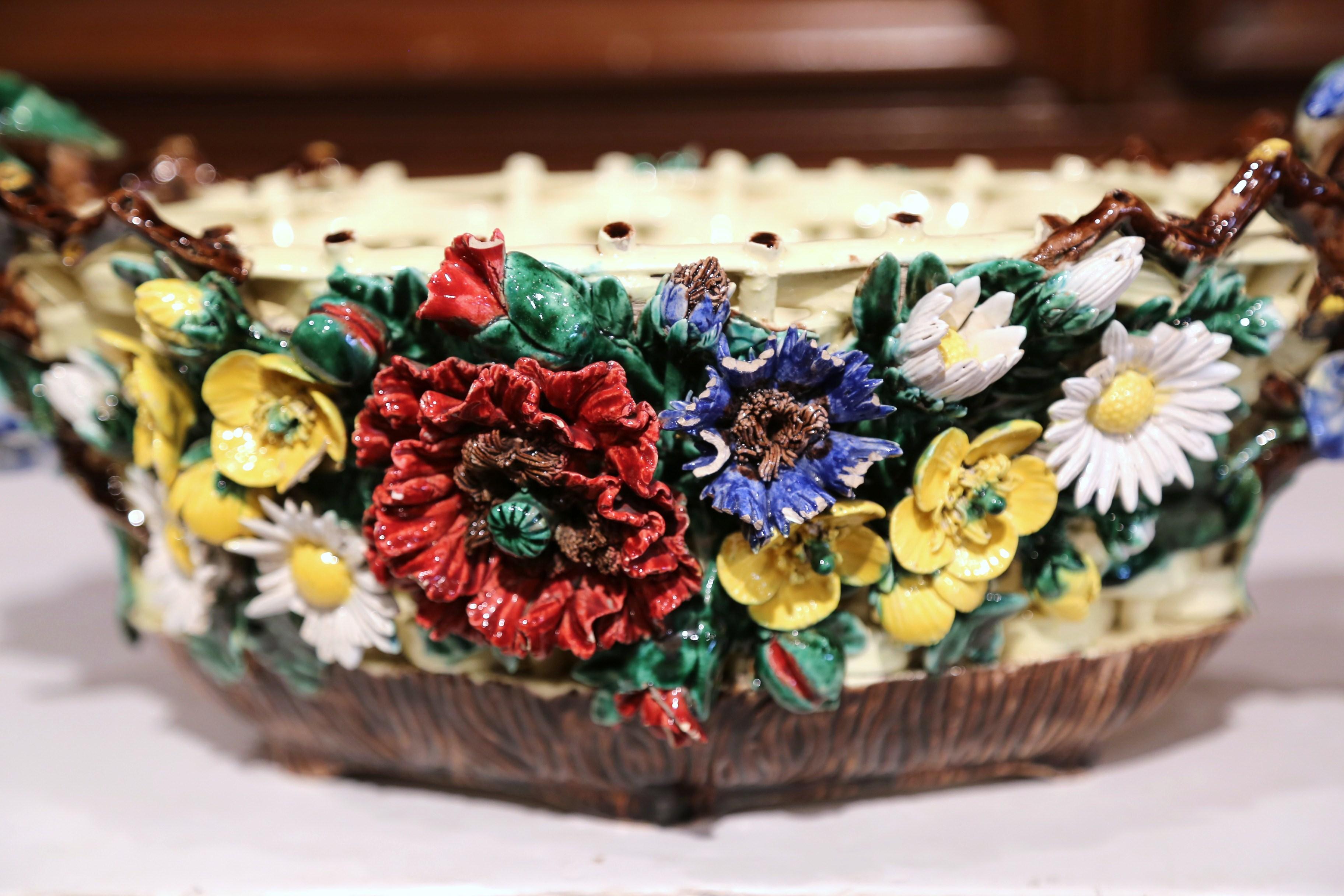 Decorate any tabletop in your home with this elegant, antique Majolica jardinière. Crafted in France, circa 1860, the colorful planter has an intricate basket weave motif at the base, embellished with hand painted flowers on both sides. The handles