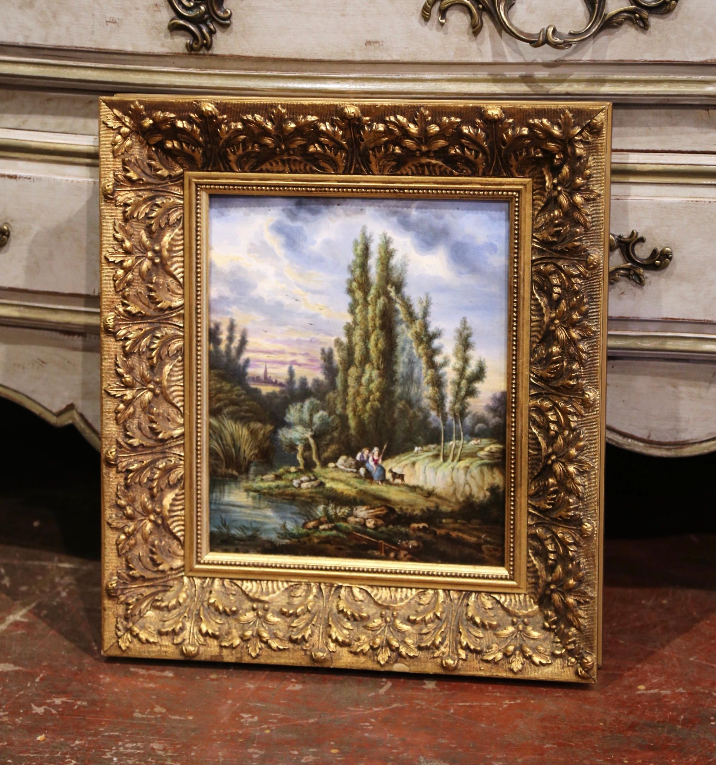 This antique porcelain plaque was hand painted in France, circa 1870. The composition depicts a pastoral scene with a shepherd and shepherdess sitting on a rock surrounded with trees and pond. The Classic French hand painted art work is set in an