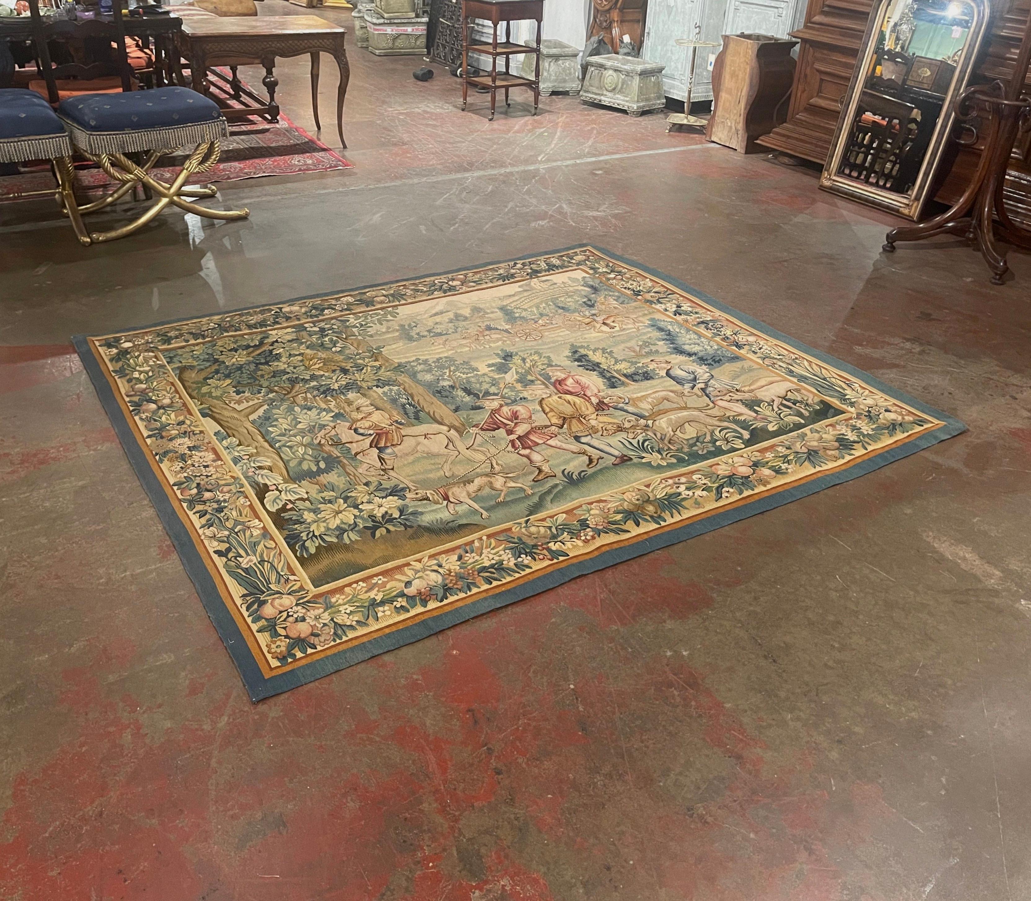 Decorate a wall or a staircase with this elegant and colorful antique hunt tapestry with original border. Handwoven in Aubusson, France circa 1880, the rectangular wall decor composition, depicts a landscape scenery with large trees and foliage