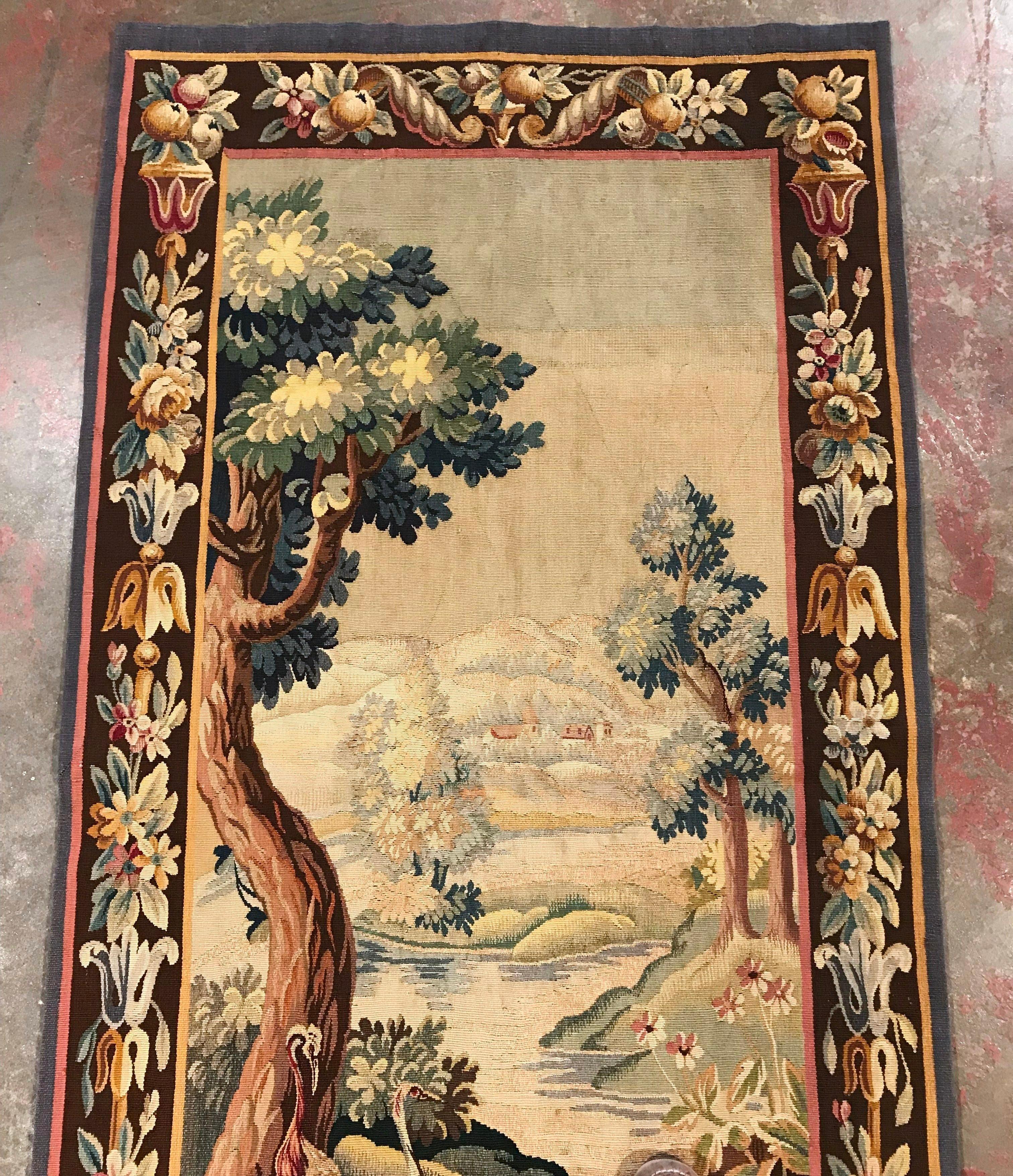 Place this long and narrow antique tapestry in a staircase or in between two windows for a pop of color. Handwoven in Aubusson, France, circa 1860, the colorful, verdure wall piece has its original fruit and floral border and features two tall