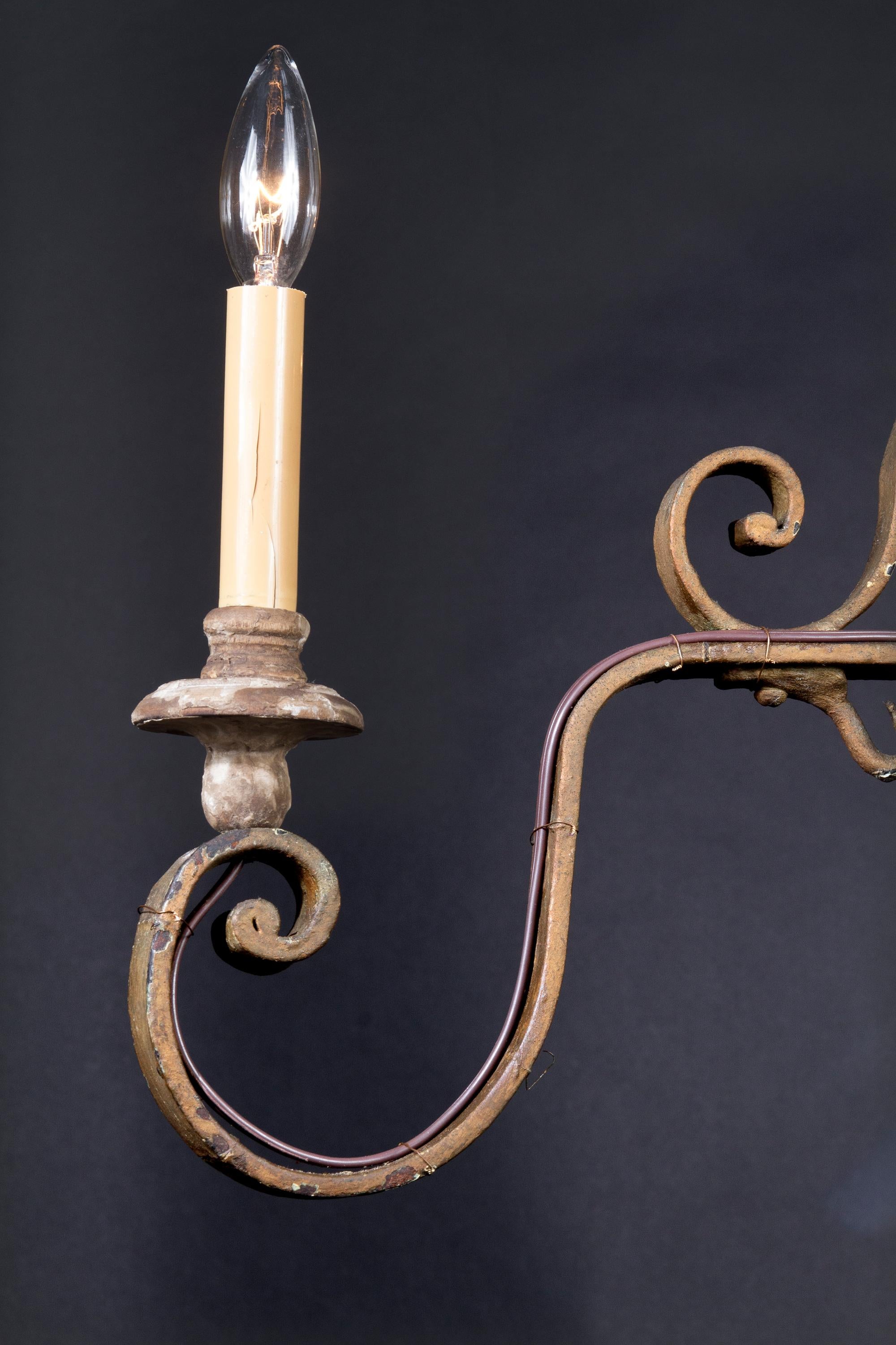 Questo antico lampadario francese in ferro battuto a mano risale al XIX secolo e presenta una splendida lavorazione a volute su tutta la corona e i quattro bracci. Il design è classico e lineare, in grado di adattarsi a qualsiasi spazio.