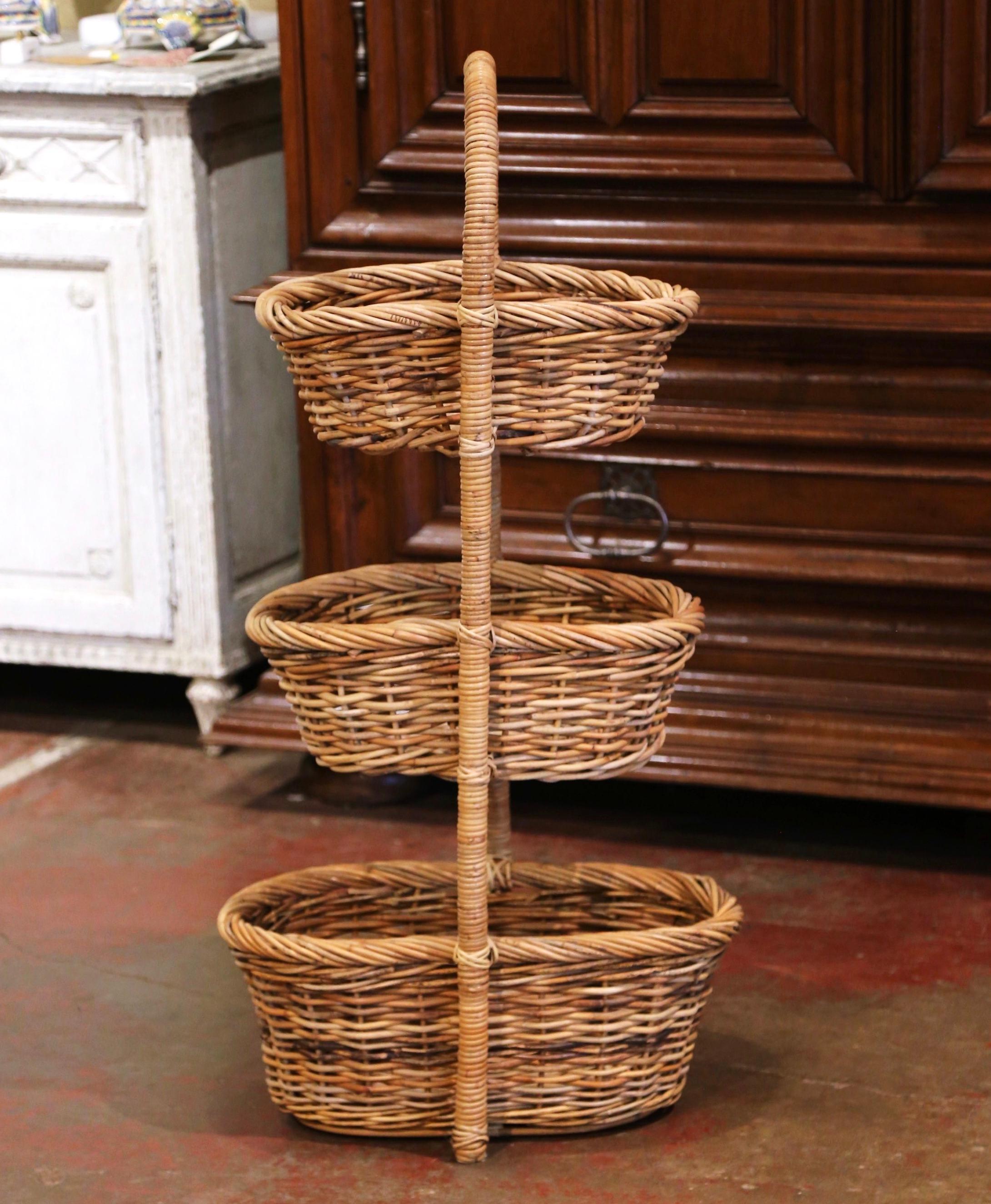 Created in the Normandy region of France circa 1880 and made of handwoven wicker, the antique basket was originally for apple picking and display. The tall three-tier piece features a large wooden handle at the pediment over a trio of stacked oval