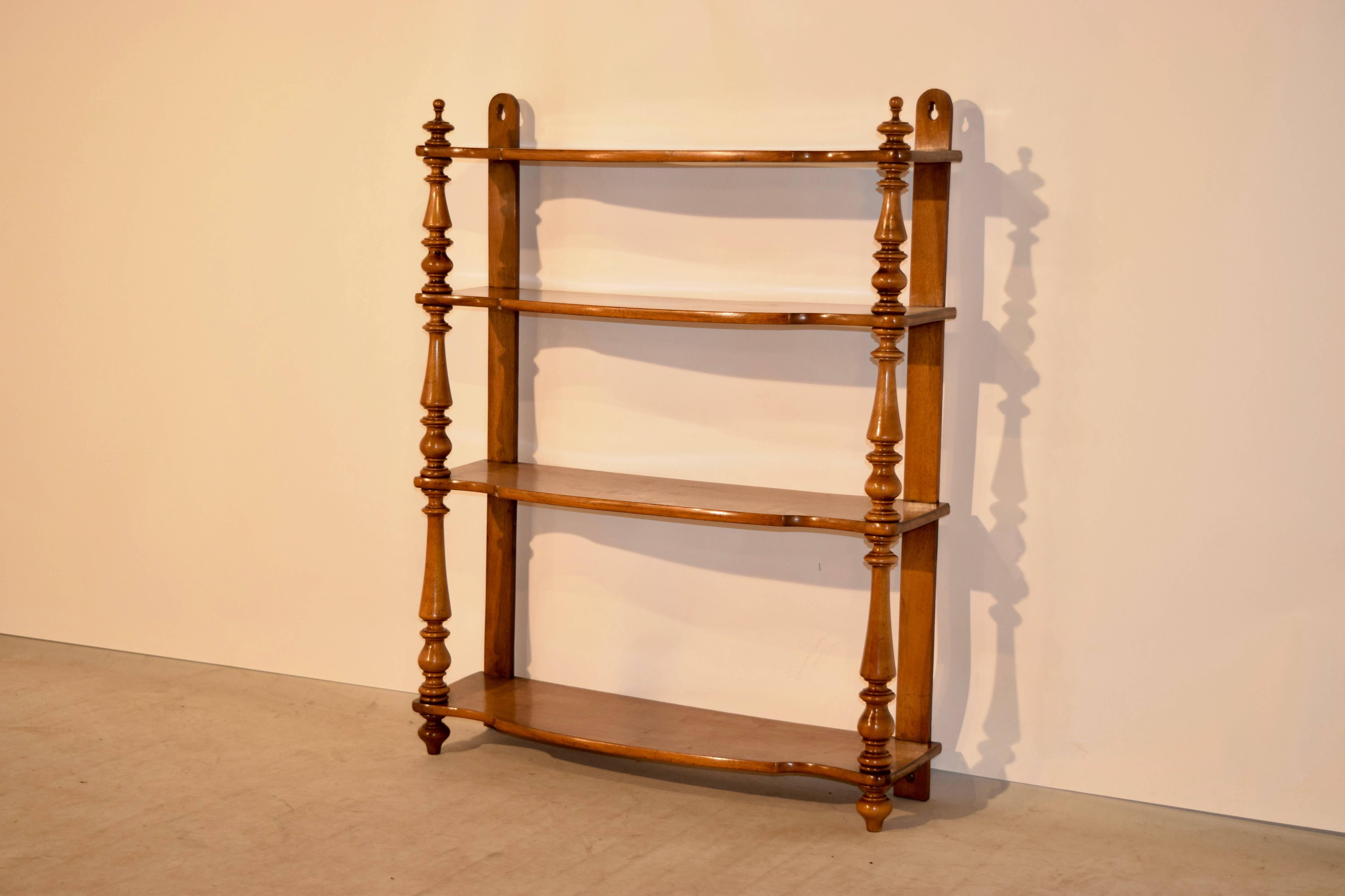 19th century French hanging shelf made from cherry. It has four shelves, all of which are shaped and have wonderful graining, separated by hand-turned shelf supports on the front and flat back supports for easy placement against a wall.