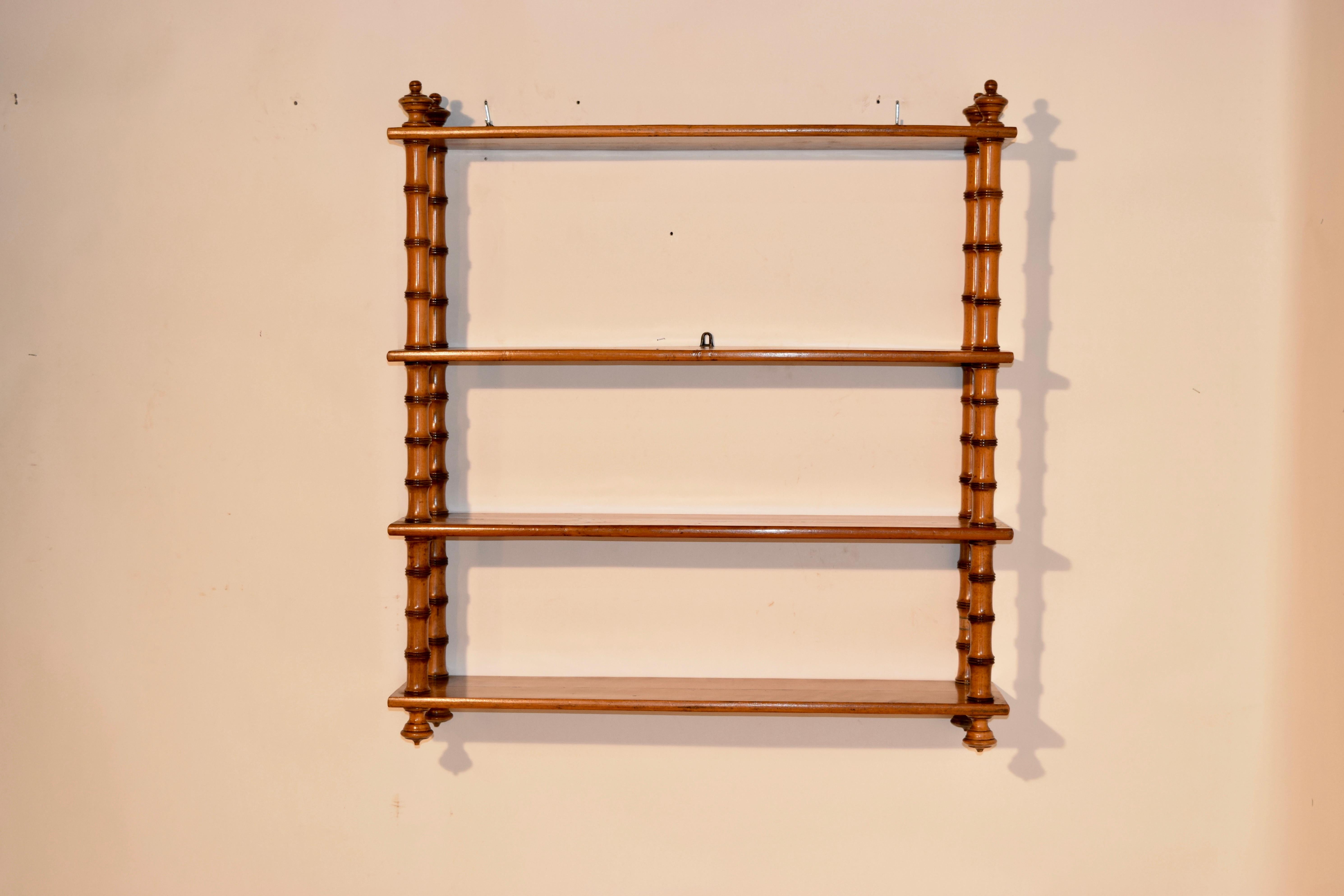 19th century hanging shelf made from cherry from France. The top and bottom are decorated with hand turned finials and has four shelves which are separated by hand turned shelf supports in the style of faux bamboo turnings.